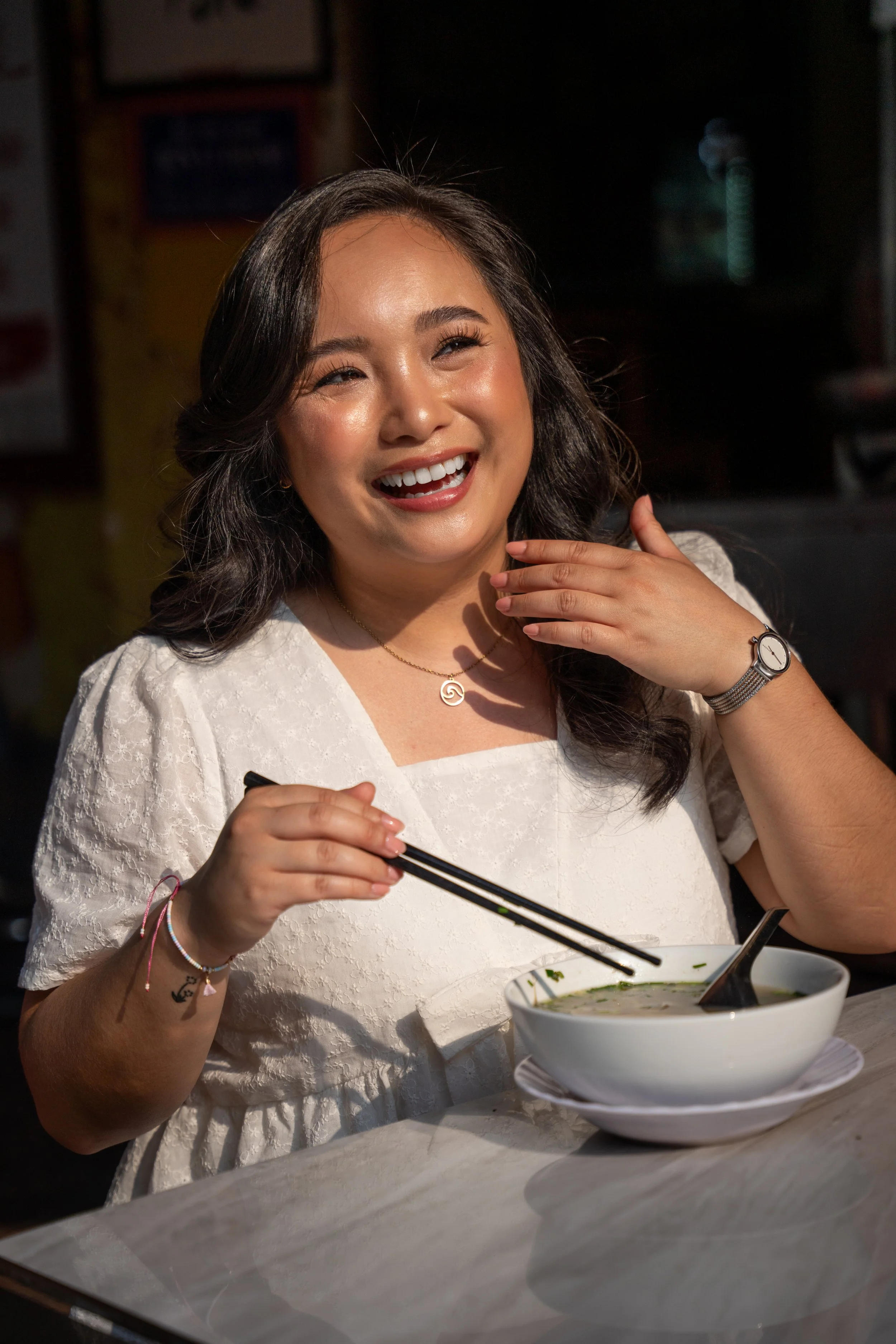 Woman laughing and eating pho in Vietnam.