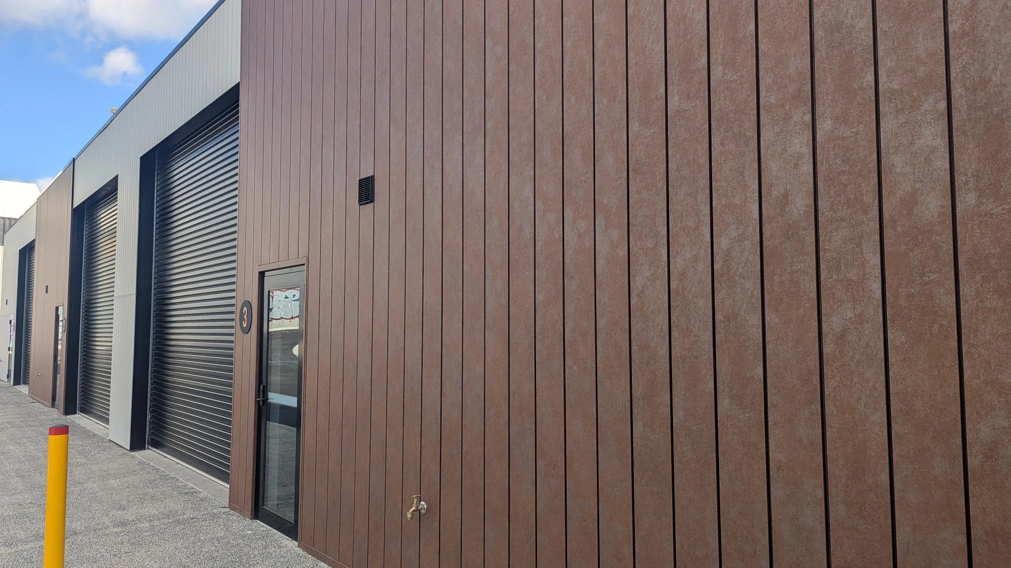 Exterior view of a commercial warehouse clad with Structuur Interlocking Panel, installed by FHRC on behalf of BlackCap in Kingston, Hobart