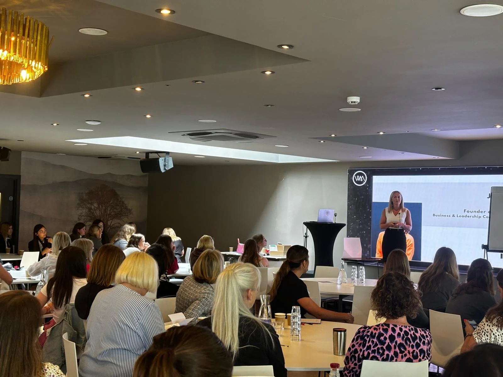 Jess Wiggins speaking at a conference about impact and leadership coaching.