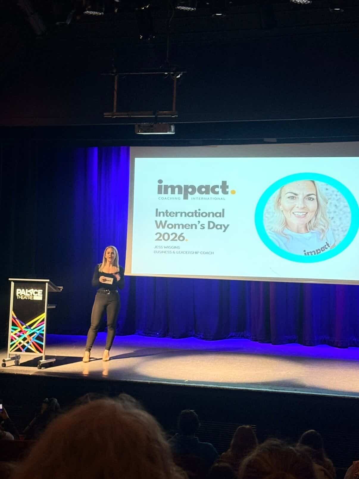 Jess Wiggins speaking on stage at an International Women’s Day event about impact.