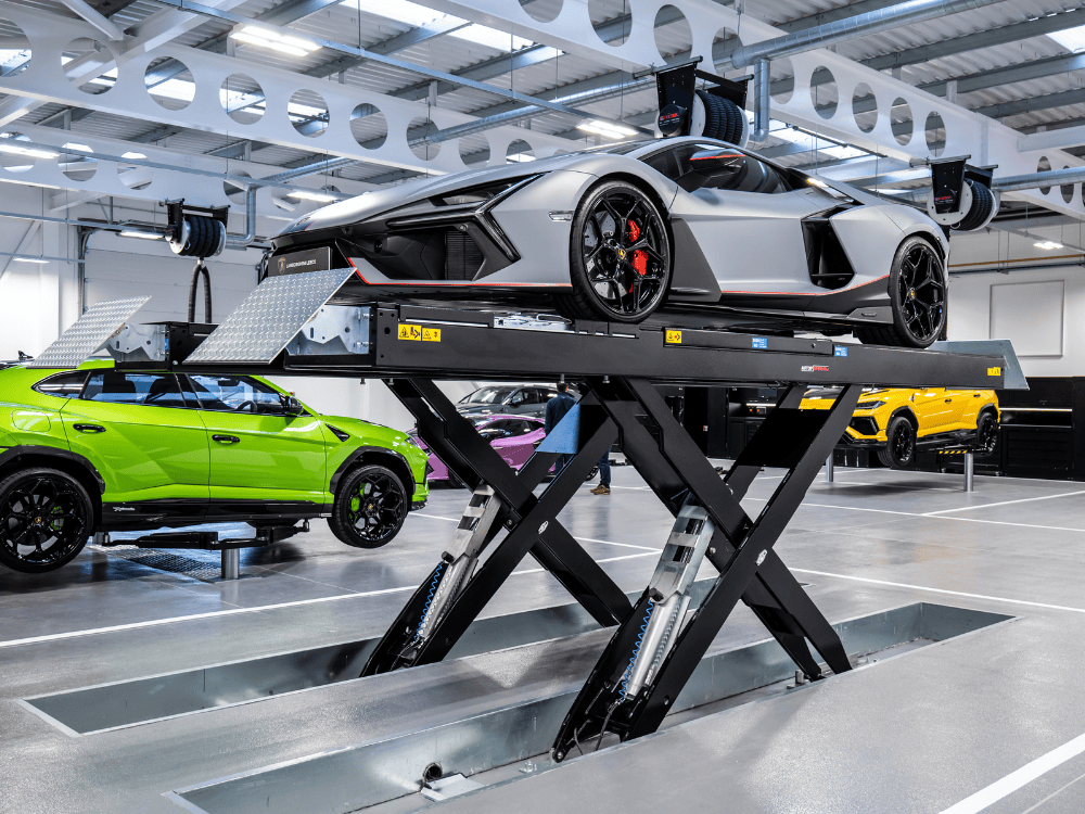 Image of shiny supercars on scissor car lifts in a white, clean garage
