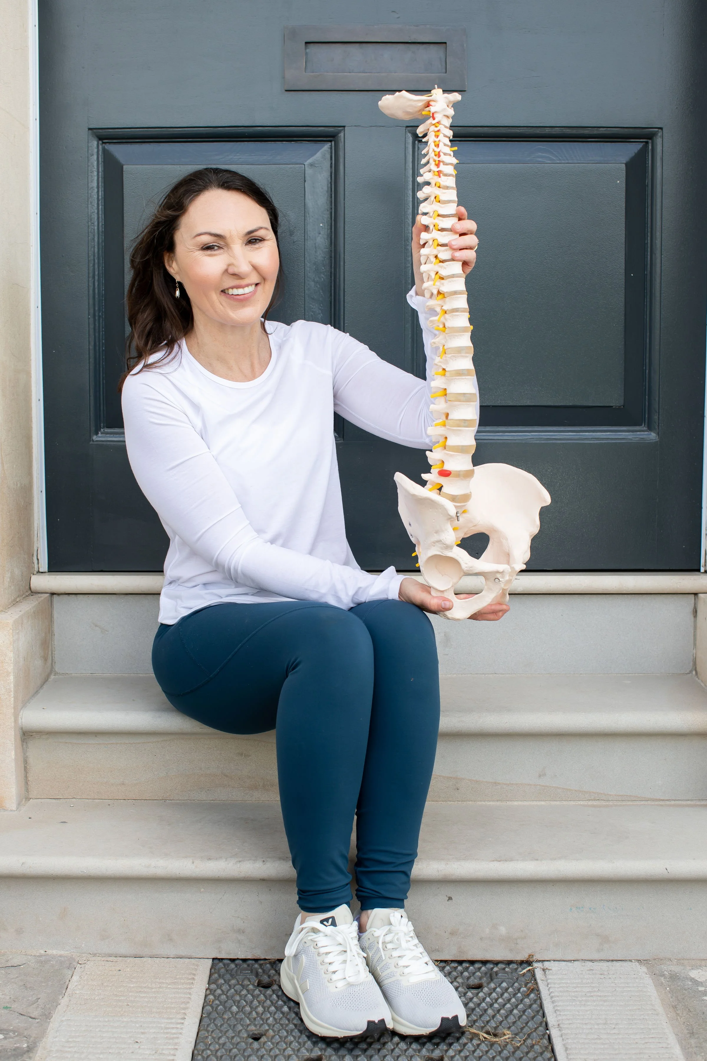 Lady sat on front door step holding a plastic spine