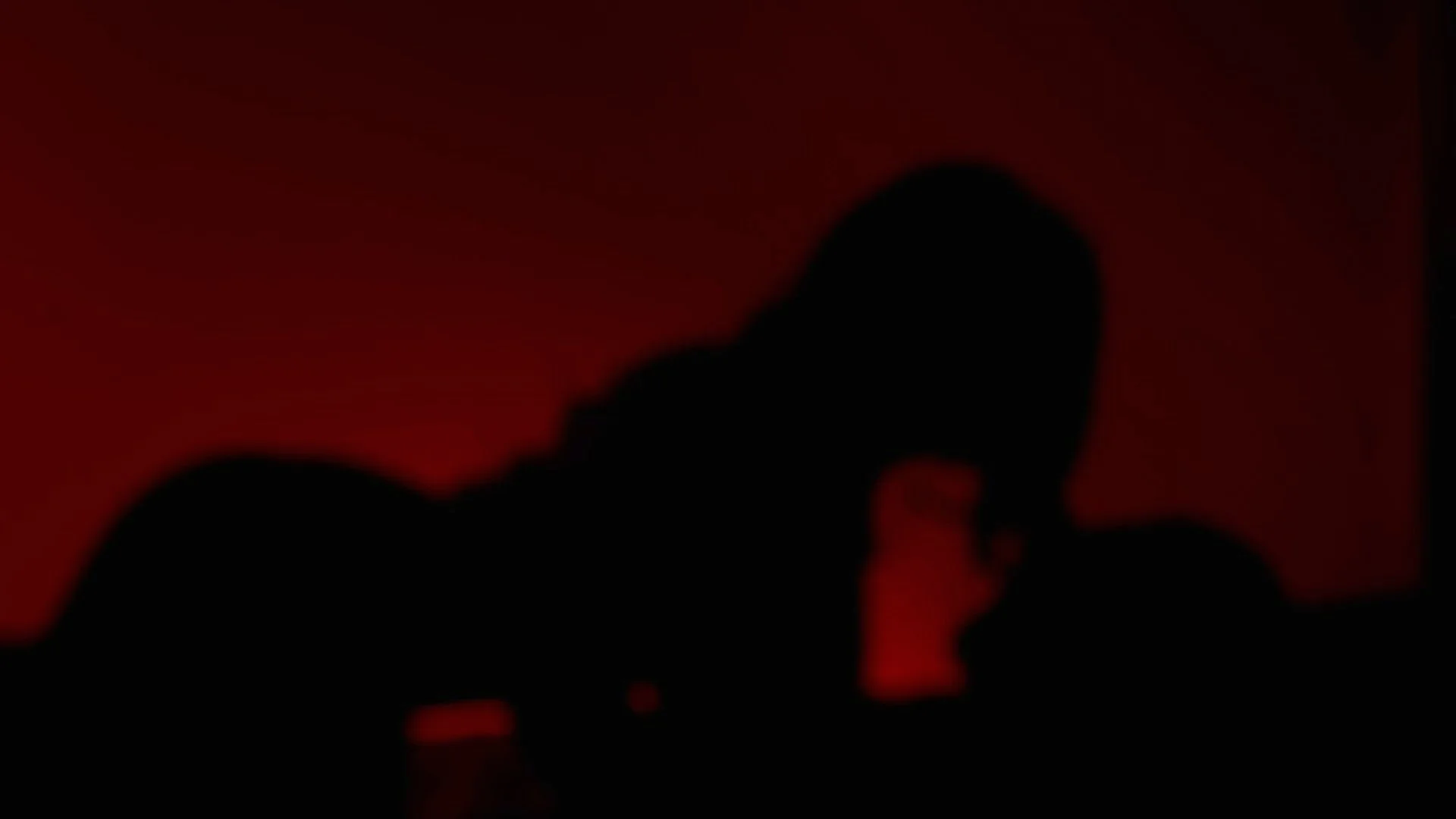 Silhouette d'une personne en méditation ou en prière, avec un arrière-plan rouge foncé.