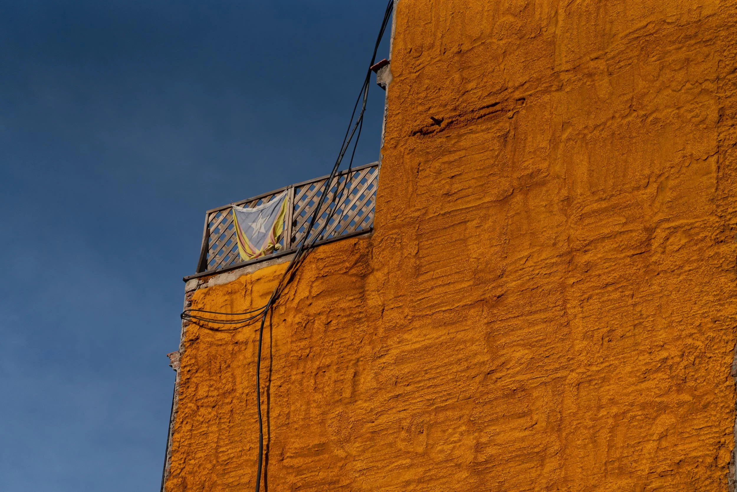 Balkon mit Wäschestück vor einer orangefarbenen Wand bei Sonnenuntergang