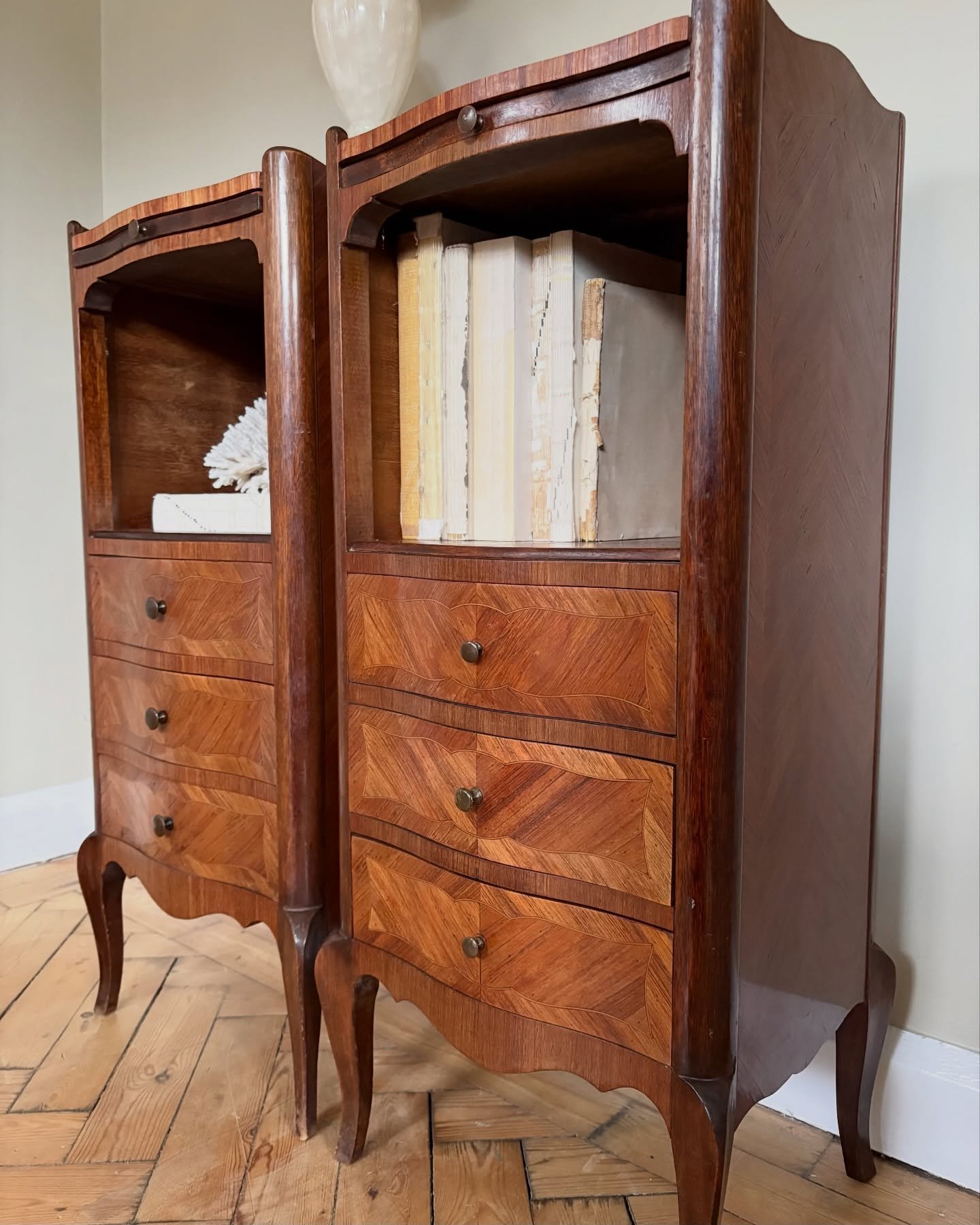 A stunning pair of French Louis XV bedside tables, boasting slender lines and exquisite Art Nouveau detailing, complete with cabriole legs and decorative parquetry veneer. Standing taller than most, they offer ample storage with deeper drawers and ge