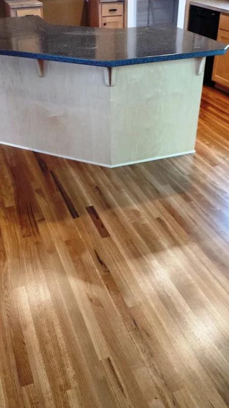 Kitchen featuring a polished hardwood floor and a kitchen island with a black countertop.