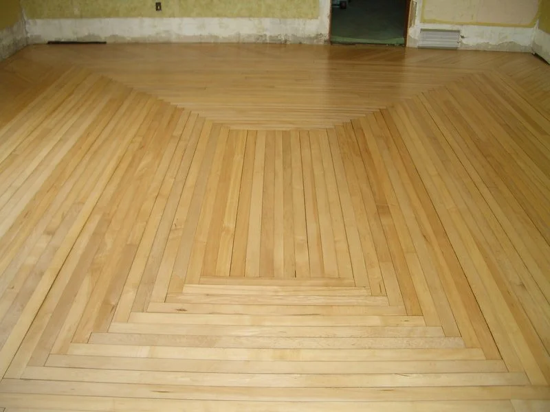 Wooden parquet floor with geometric pattern in an empty room.