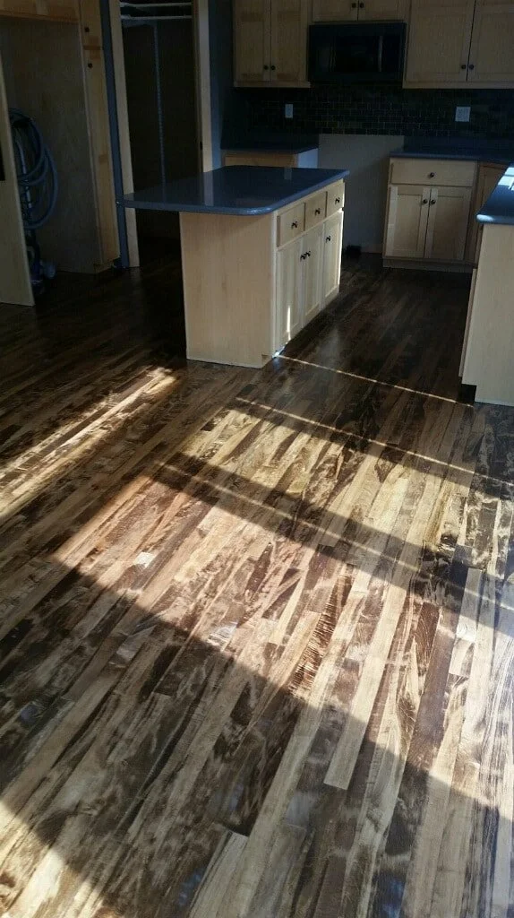 Kitchen with wooden flooring, light-colored cabinets, and a central island with a dark countertop.