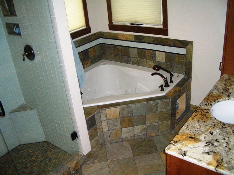 Bathroom with corner bathtub, shower, and granite countertop sink