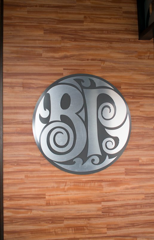 A wooden wall with a circular metallic sign featuring the stylized letters 'BP' in intricate design.
