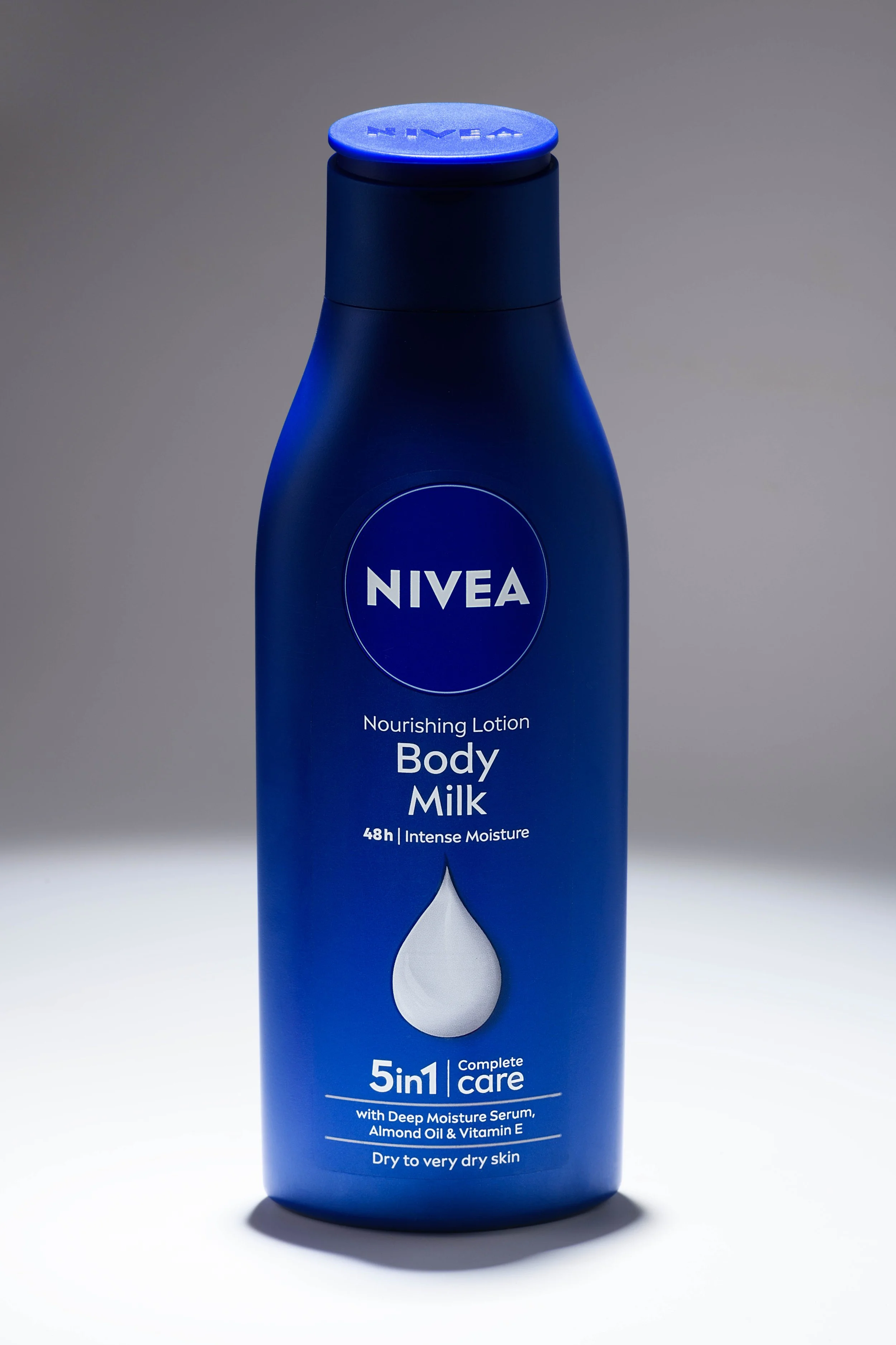 A blue bottle of Nivea nourishing body lotion, labeled for 48 hours of intense moisture, with a drop icon and details about ingredients and dry skin care.