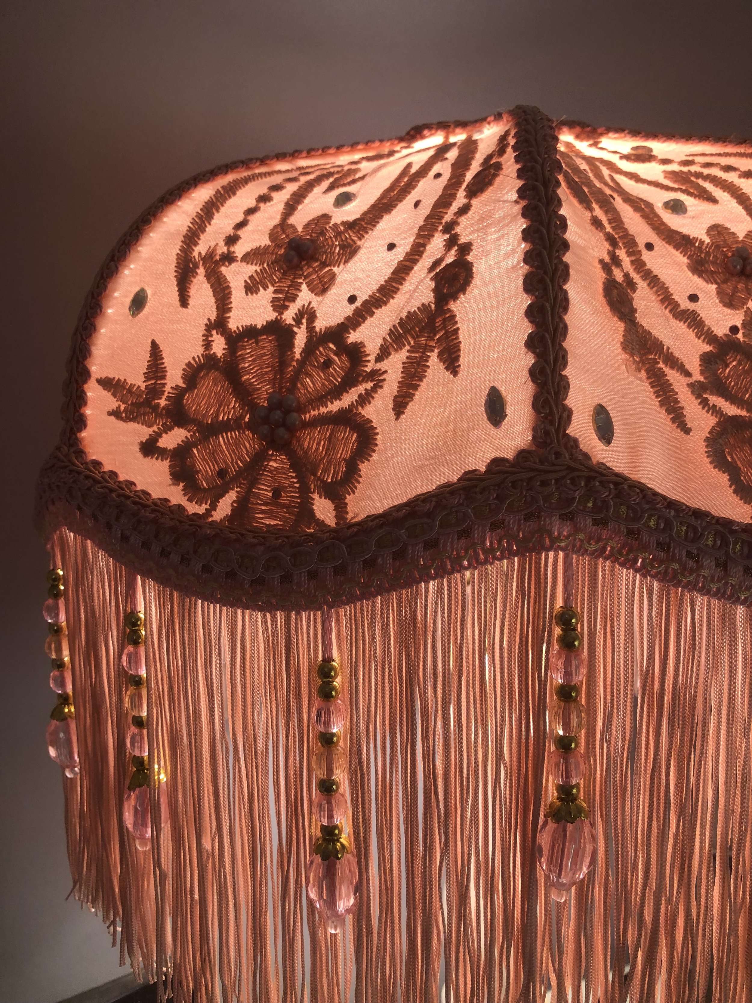 Art deco fringed lampshade in pink silk , floral lace, close up floral detail lit up