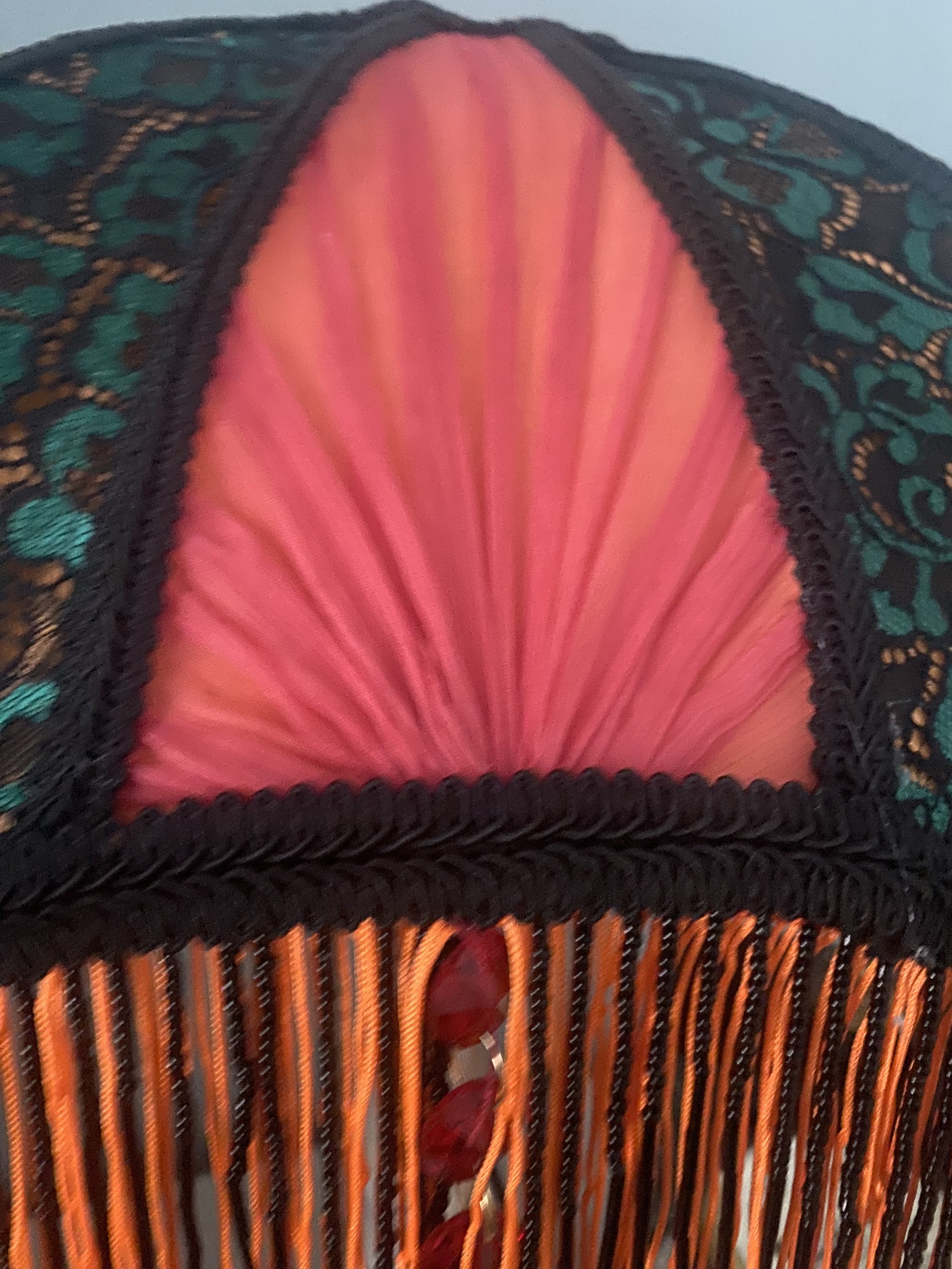 Art deco fringed lampshade in a crescent moon shape, orange silk, green and black lace, scarlet pleated panels , close up