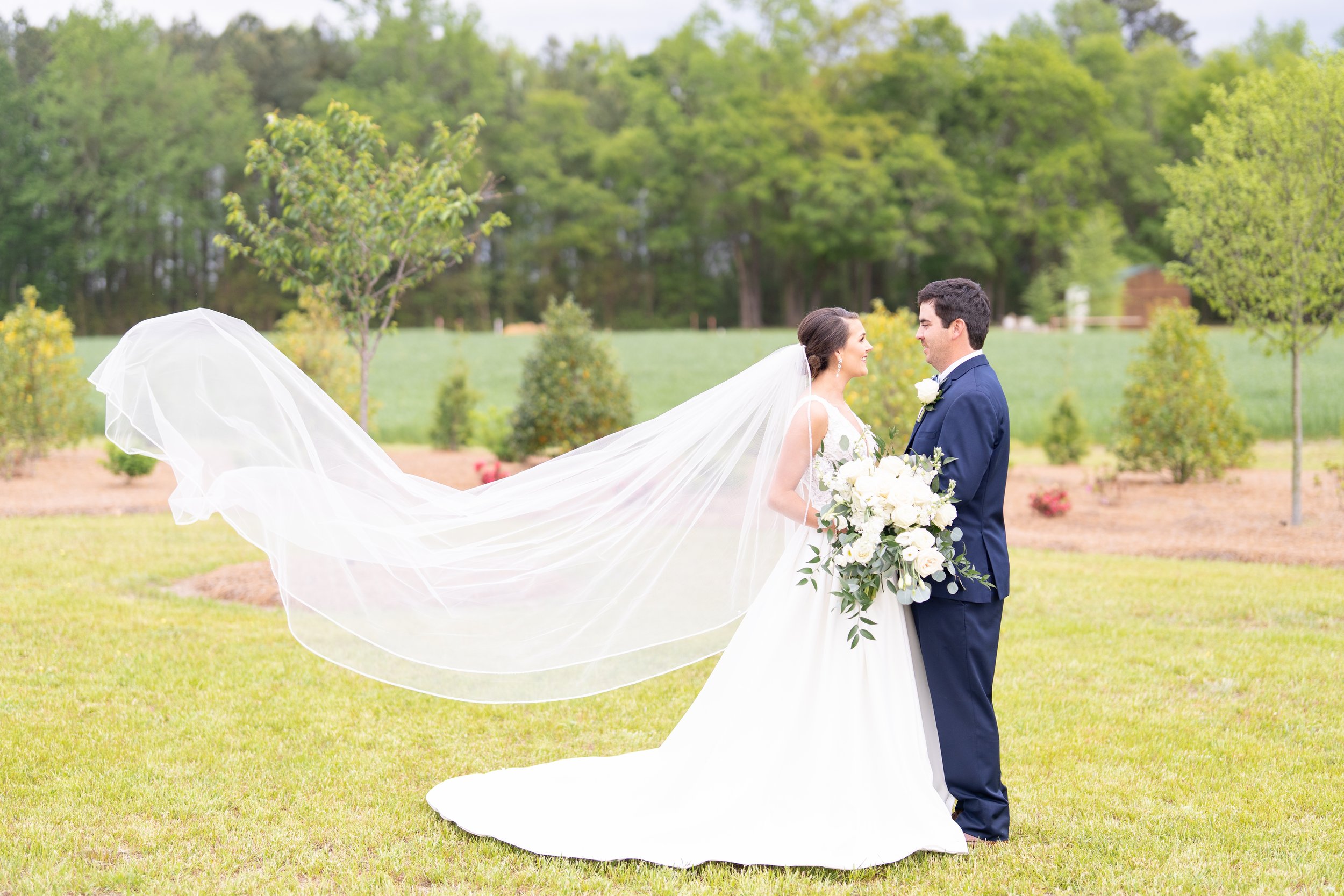Abbey Marie Photogrpahy:Brides veil is flowing in the wind while her and groom hold hands and unite with a large beatiful bouquet.