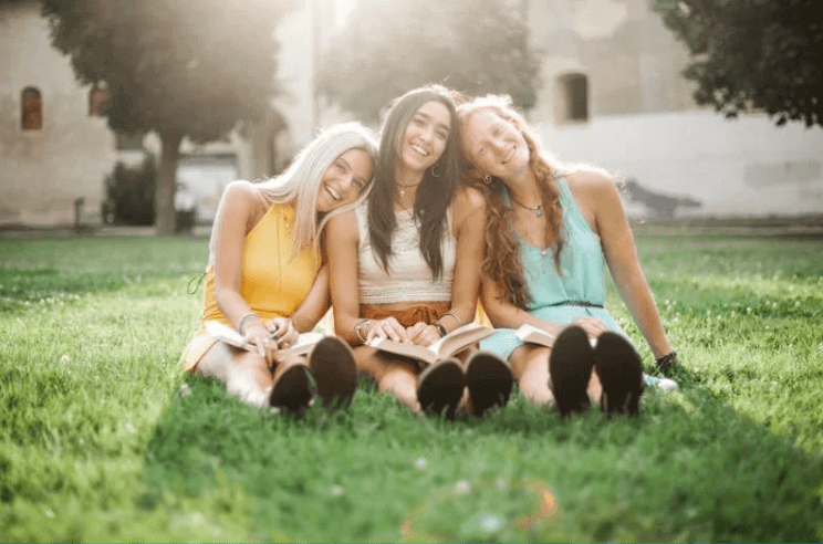 girls sitting in grass after trauma and PTSD therapy and counseling for teens in Frisco, Texas