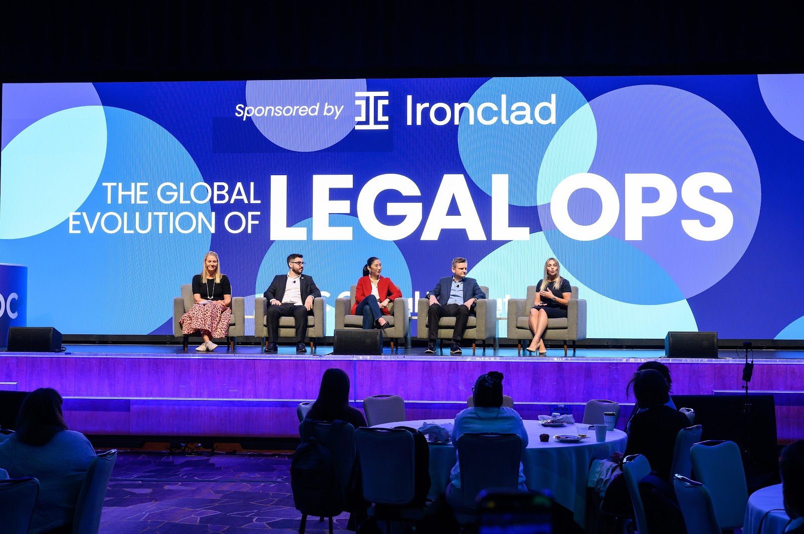 Panel discussion on 'The Global Evolution of Legal Ops' sponsored by Ironclad, featuring five speakers seated on stage with an audience in the foreground.