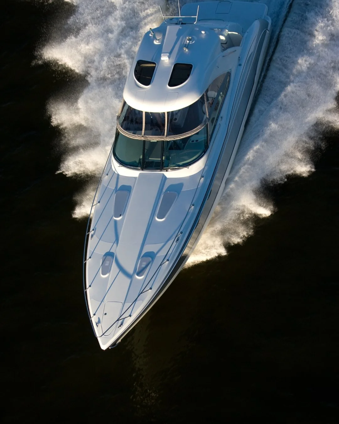 An aerial view of a luxury yacht sailing on the deep blue ocean with orange accents.