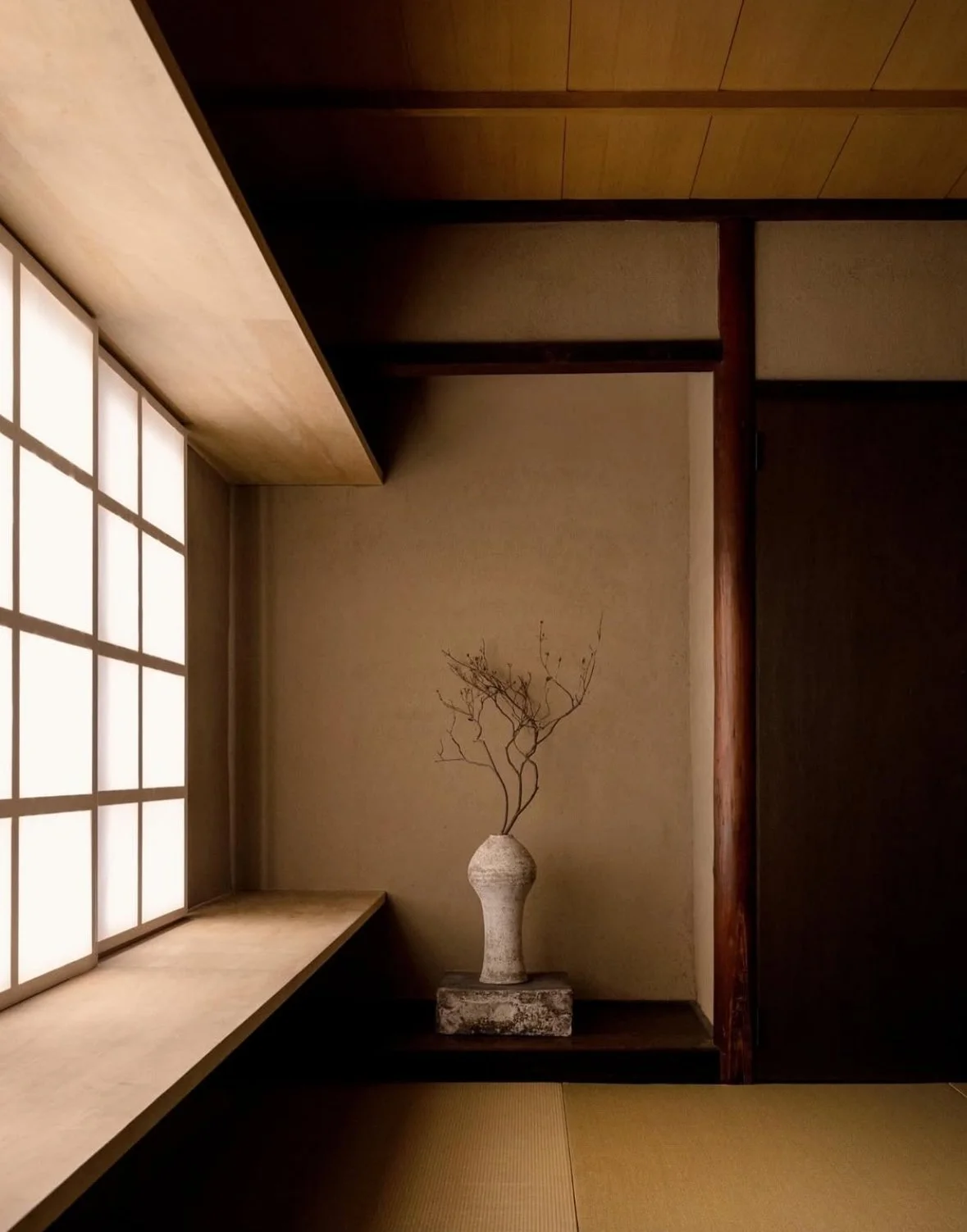 Stacked white stones placed on a black surface with green leaves hanging above, with water droplets on the leaves.