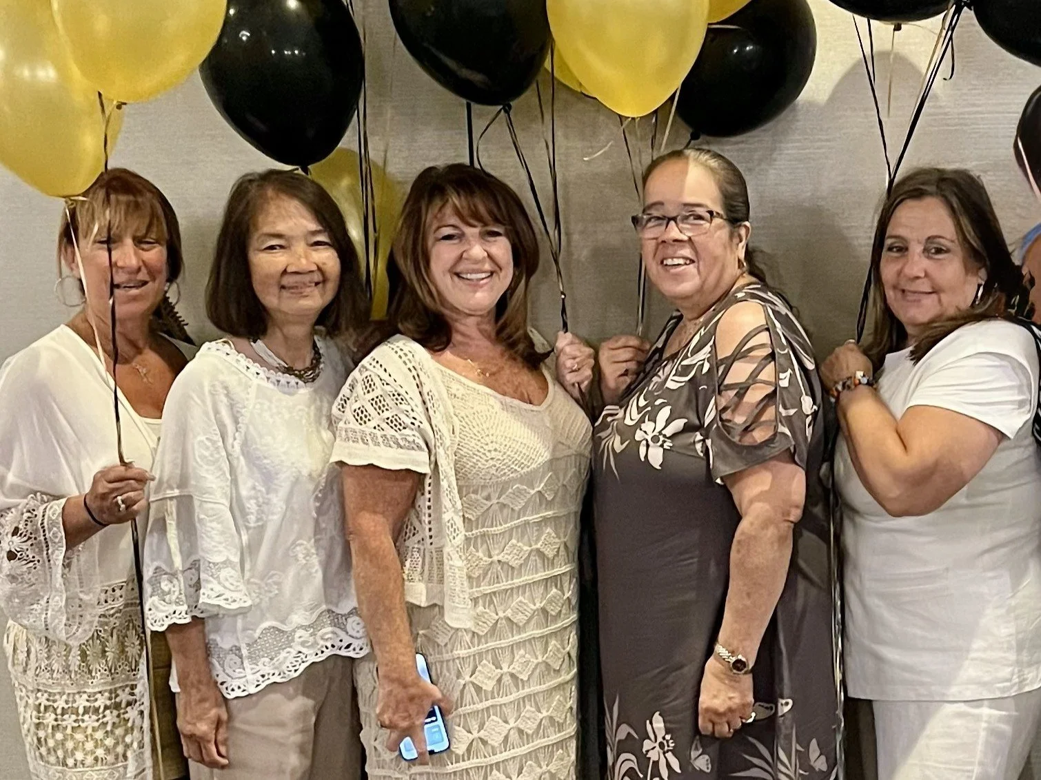 Group of five women holding balloons