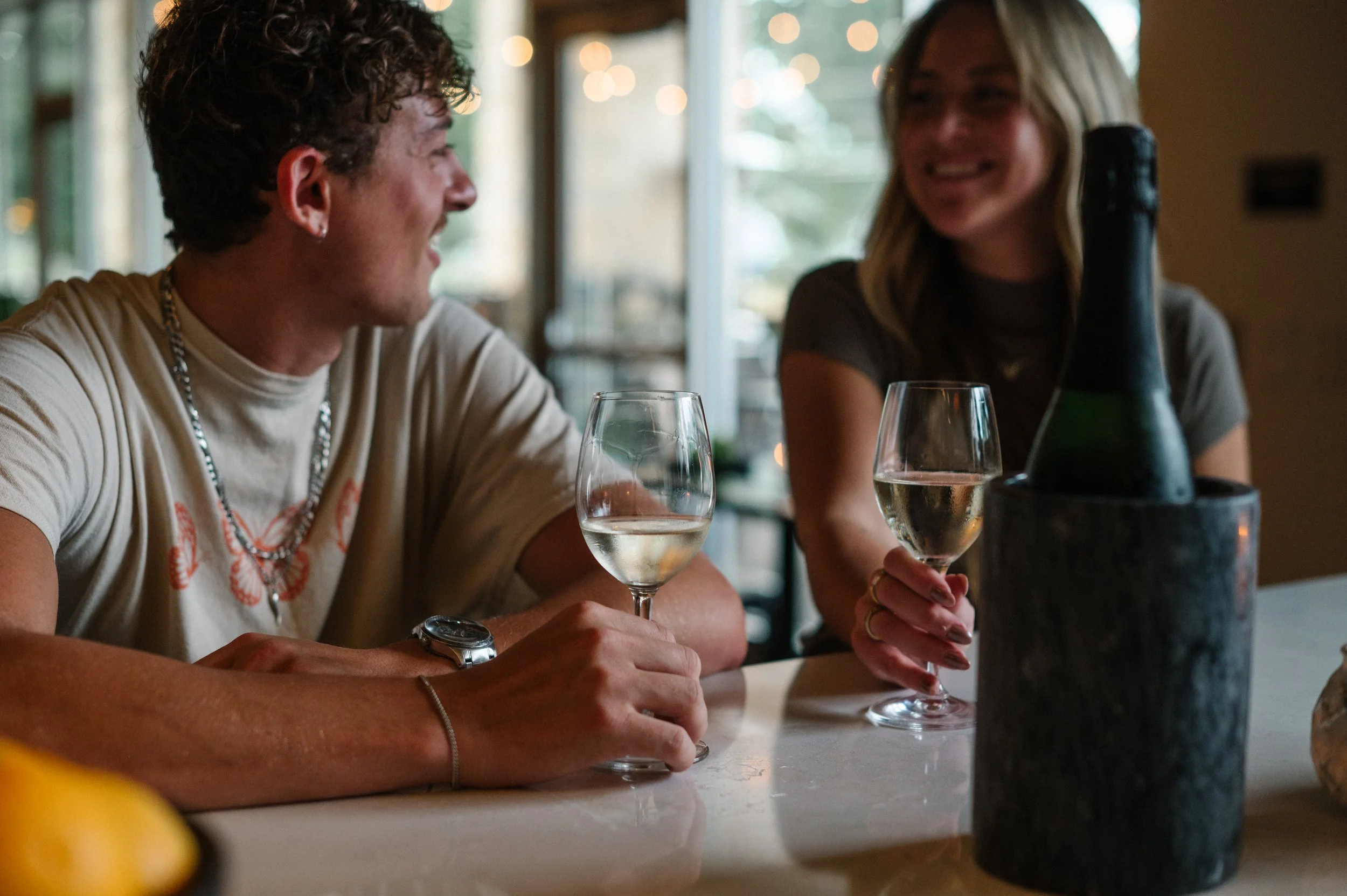 Couple sharing wood-fired pizza and cocktails at Hugo’s Wood-Fired Kitchen.