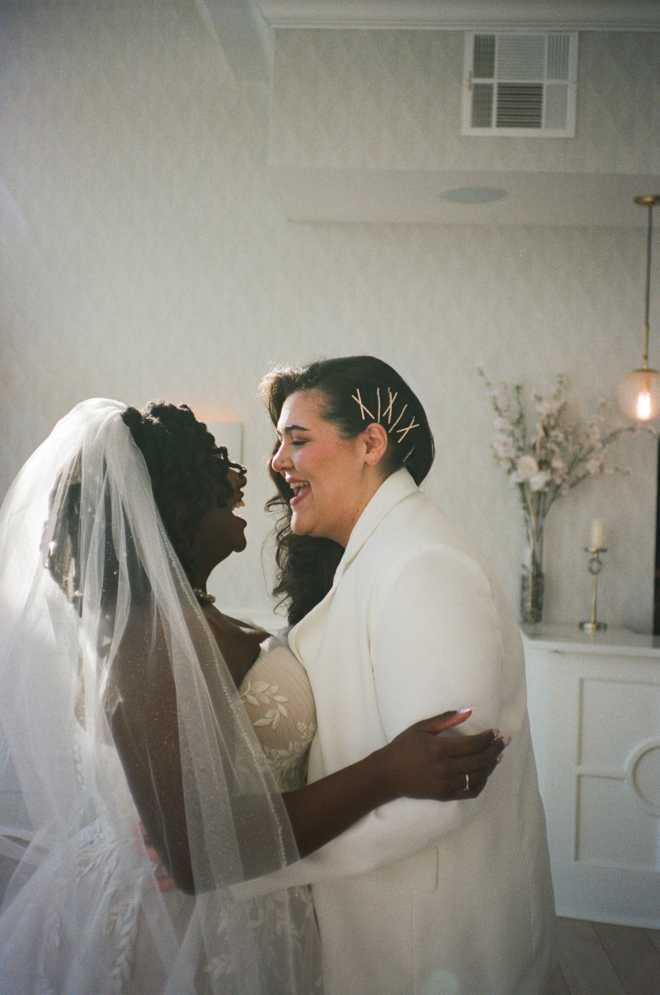 a film scan of two brides smiling and laughing with one another.