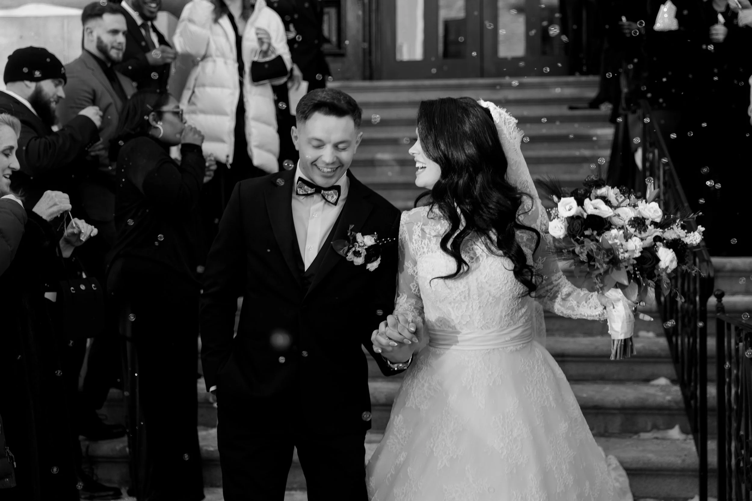 Bride and Groom exit their church ceremony surrounded by guests blowing bubbles at them. philadelphia pa