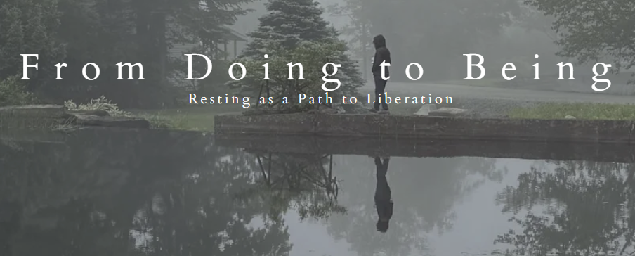 A person standing on a concrete ledge beside a calm body of water surrounded by trees in a foggy forest, with their reflection visible in the water.