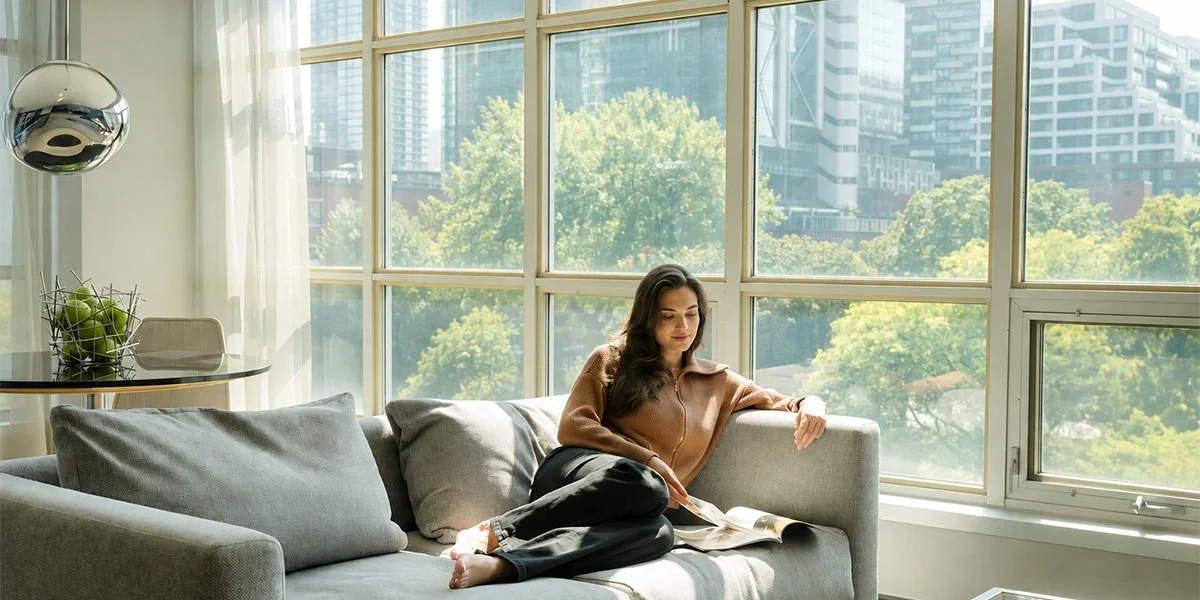 A woman reading on the sofa at a SoHo Hotel Toronto suite
