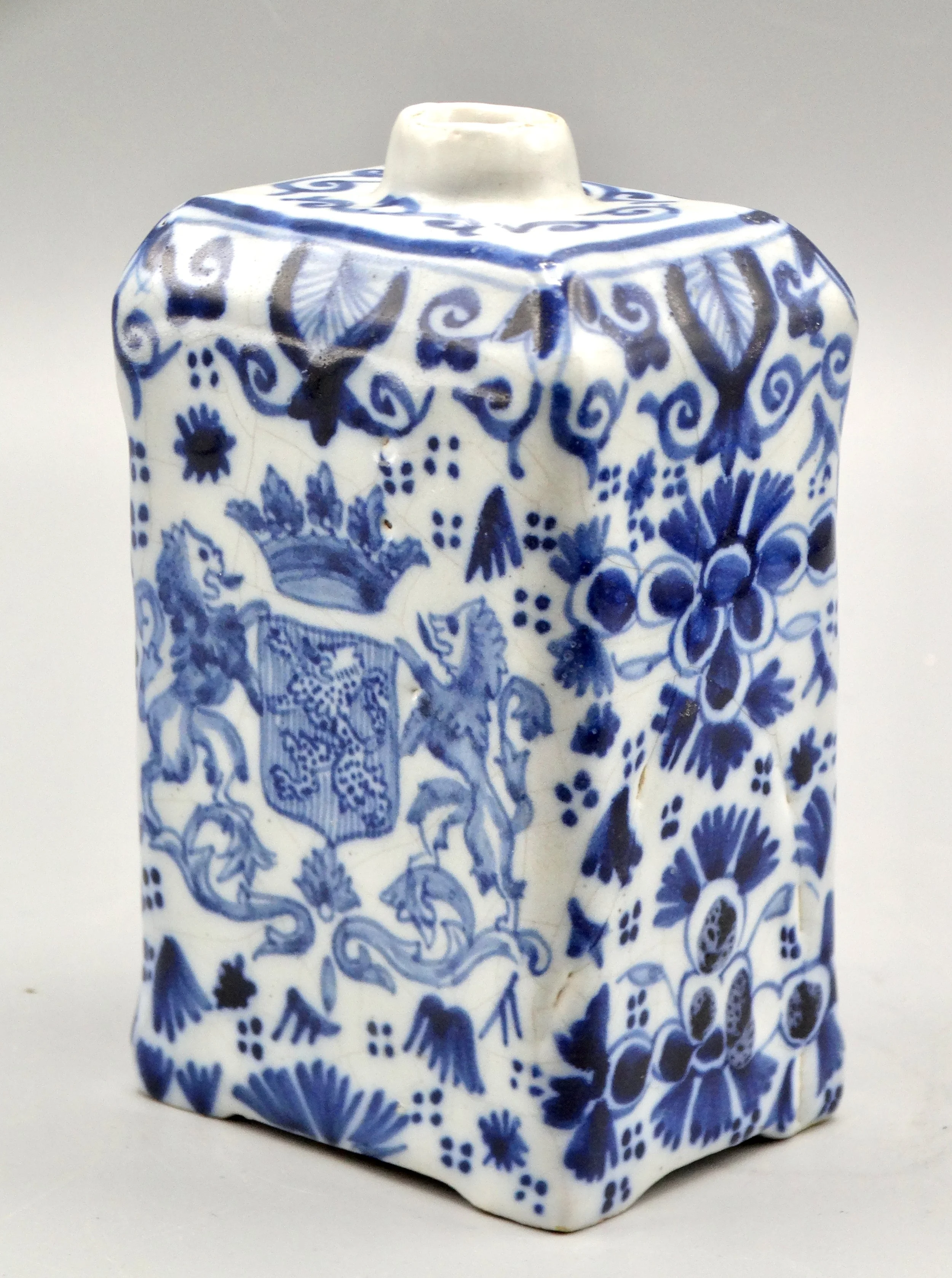19th-century English Delft tea caddy with hand painted rampart lions, crown coat of arms, bird, and floral motifs.