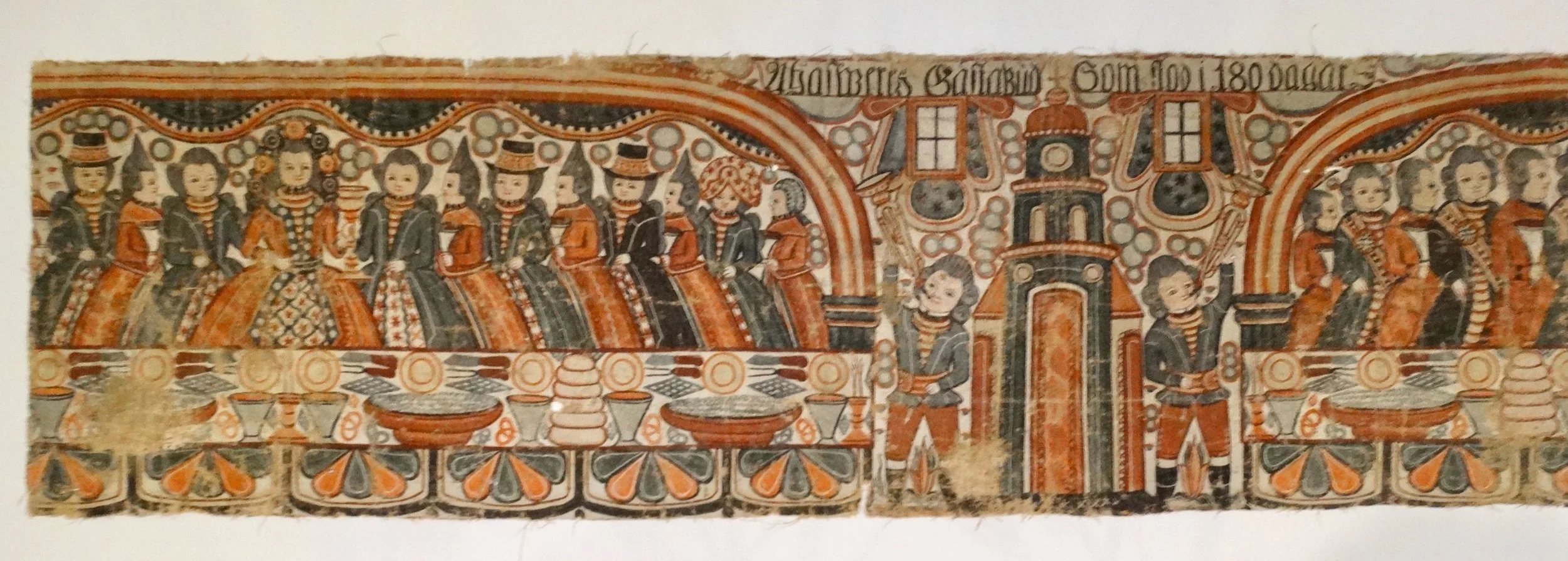 Close-up of queen’s table on Swedish bonad, showing queen and guests in colorful traditional costumes