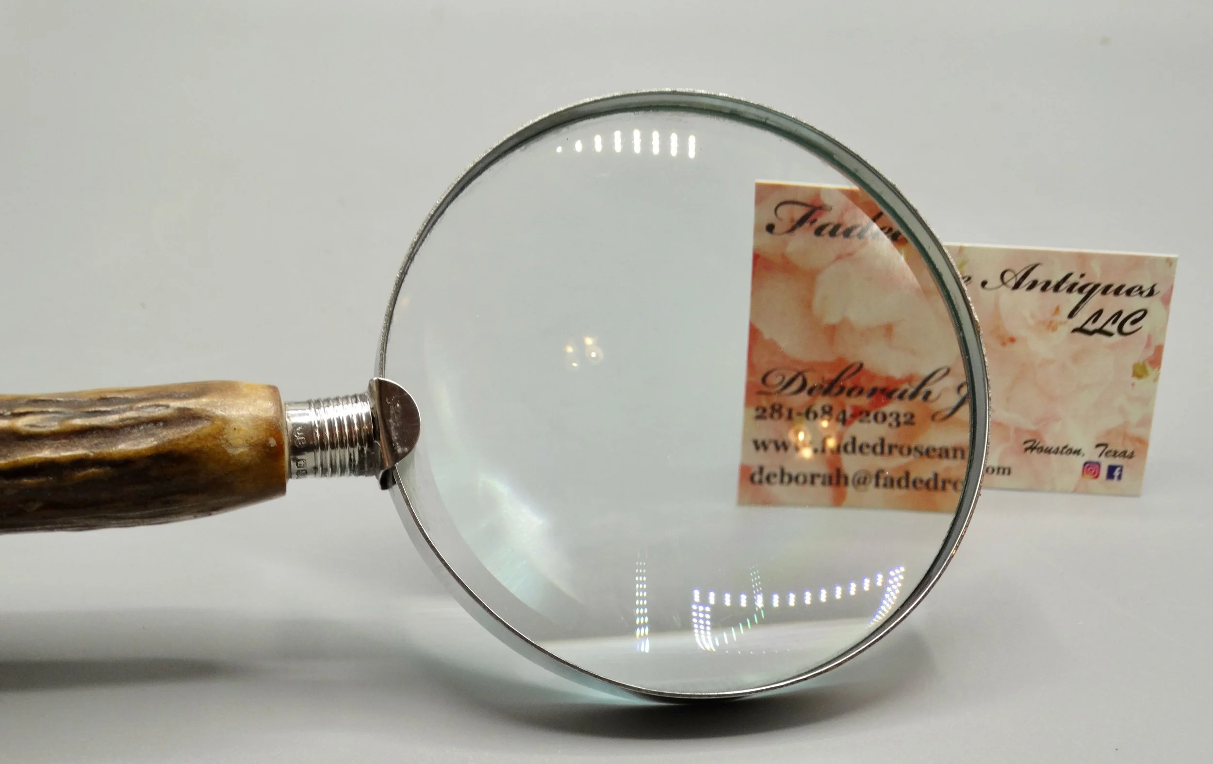 Clear glass lens fitted to antique English magnifying glass with stag horn handle and sterling mounts