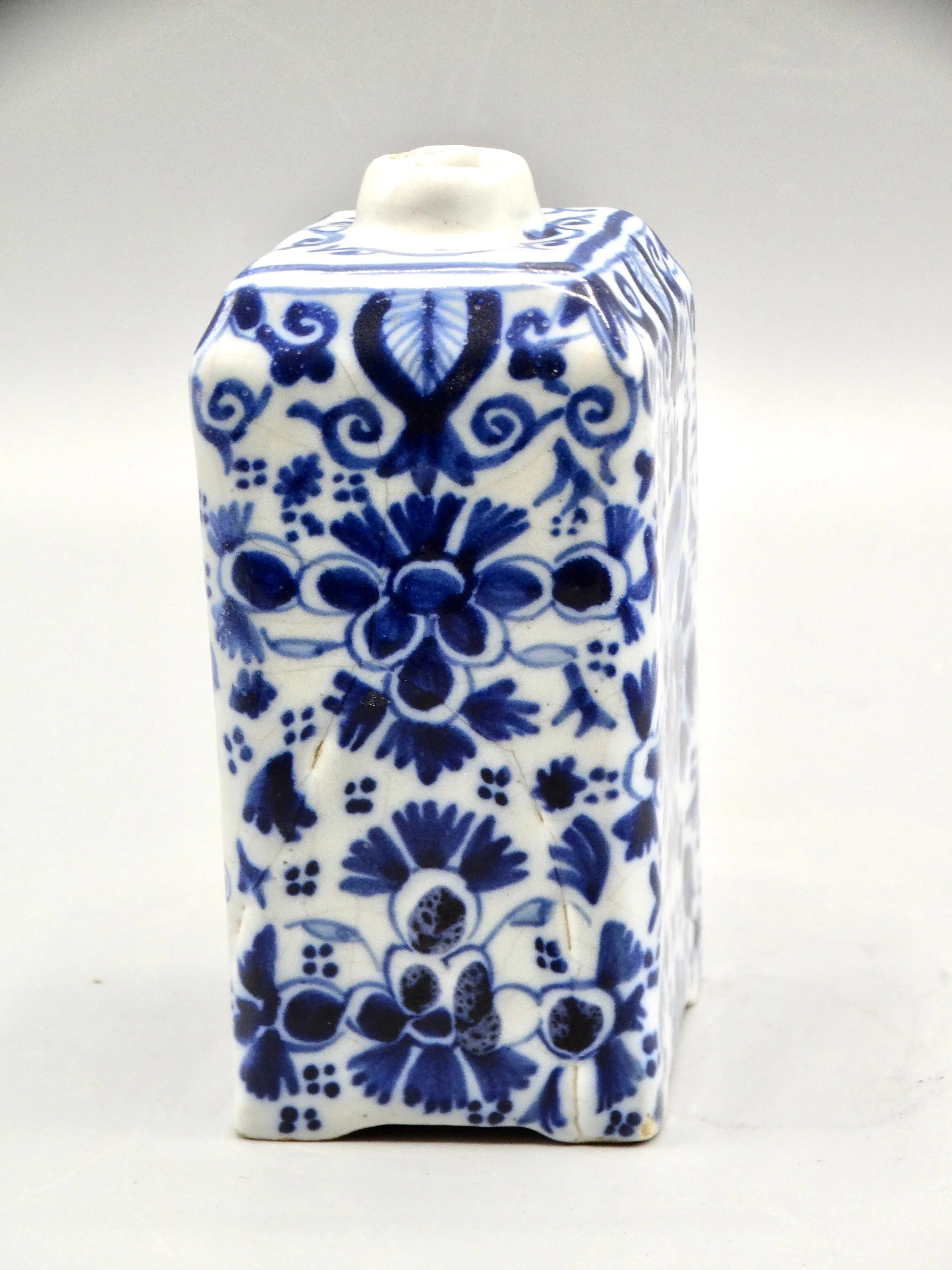Side view of 19th-century English Delft tea caddy showing form and tin-glazed surface.