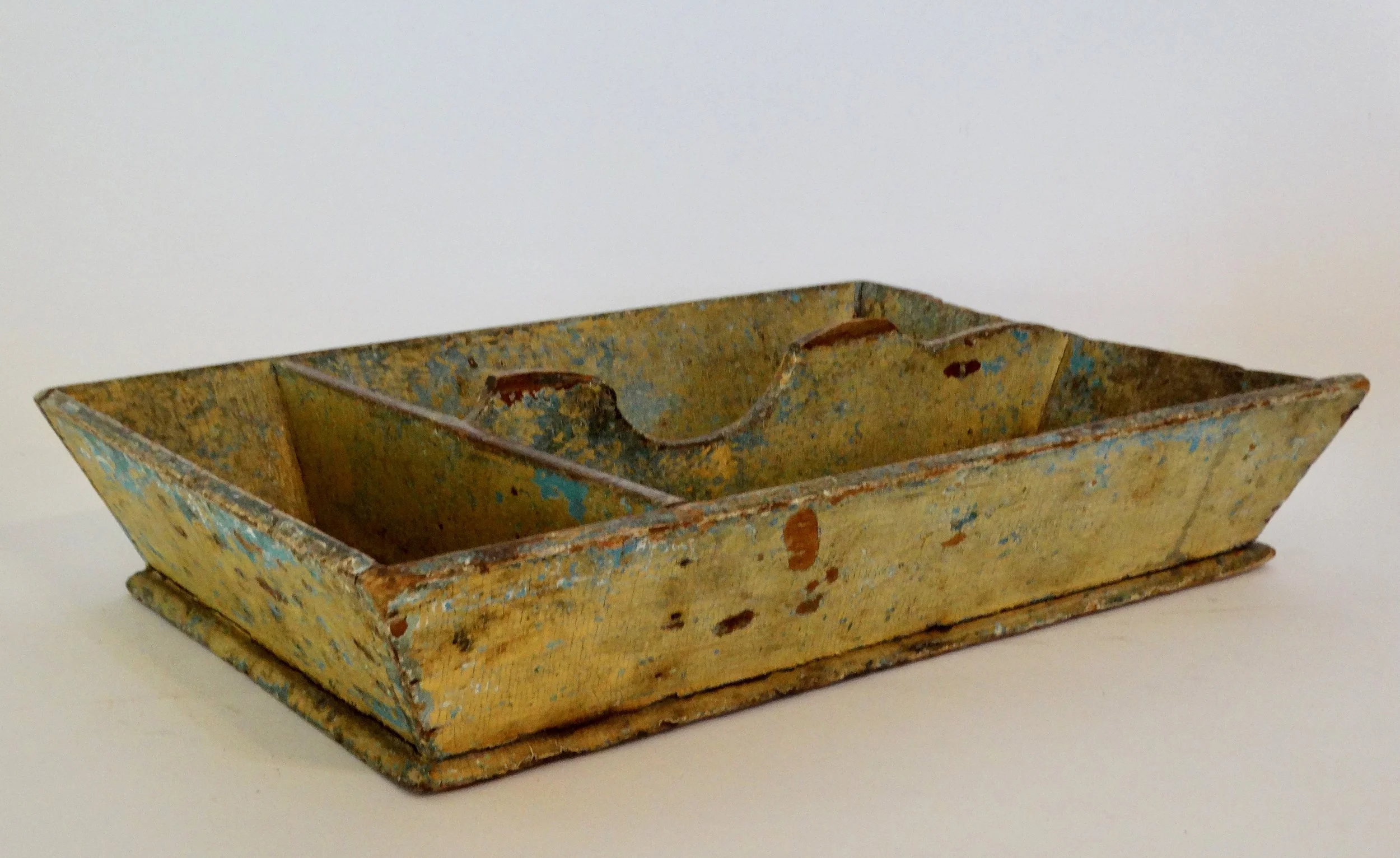 Early 19th-century American primitive cutlery tray in mustard colored paint with canted sides and protruding base.