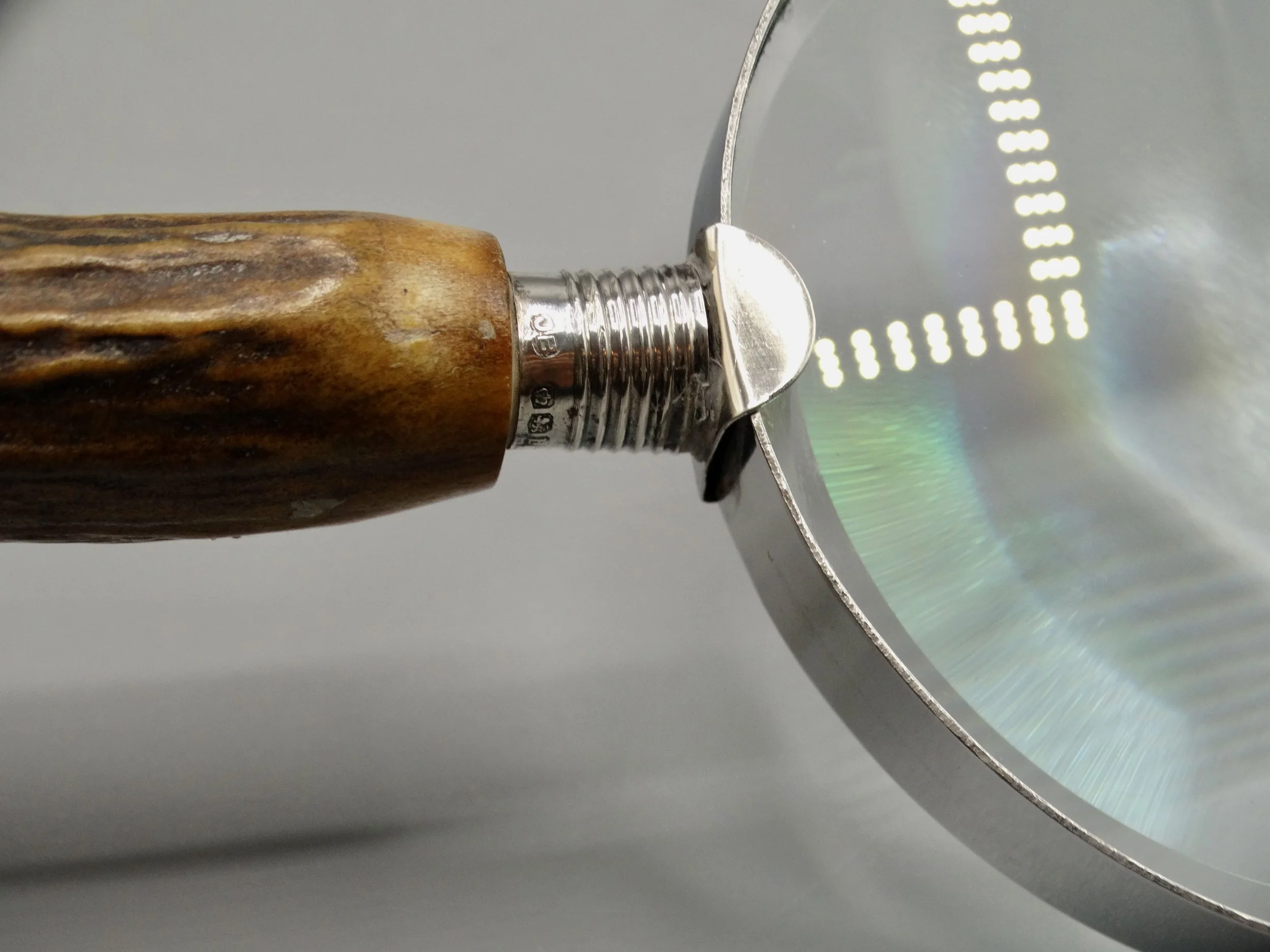 Clear glass lens fitted to antique English magnifying glass with stag horn handle and sterling mounts