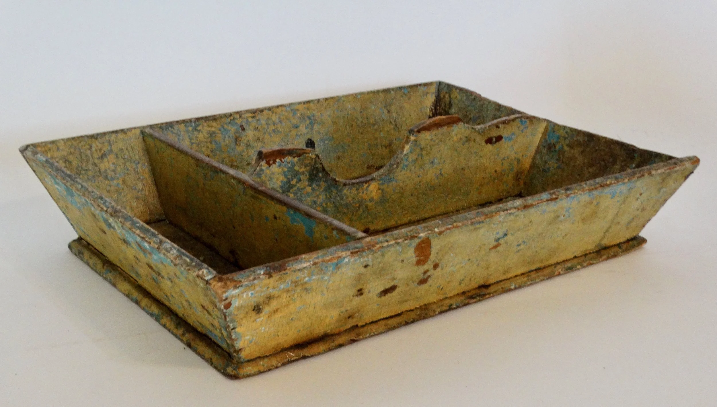 Early 19th-century American primitive cutlery tray in mustard colored paint with canted sides and protruding base.