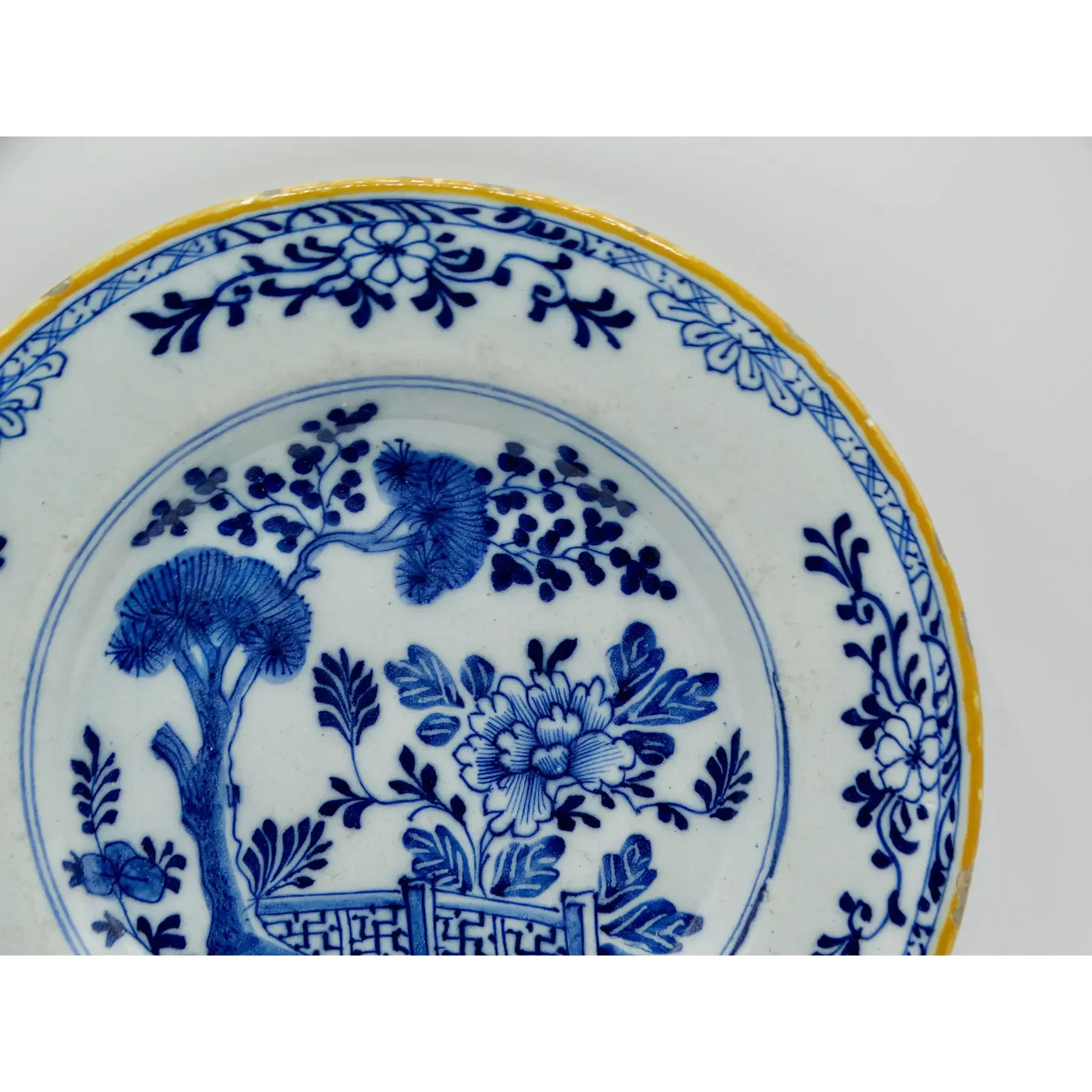 Hand painted foliate and geometric rim on 18th-century Dutch Delft chinoiserie plate.