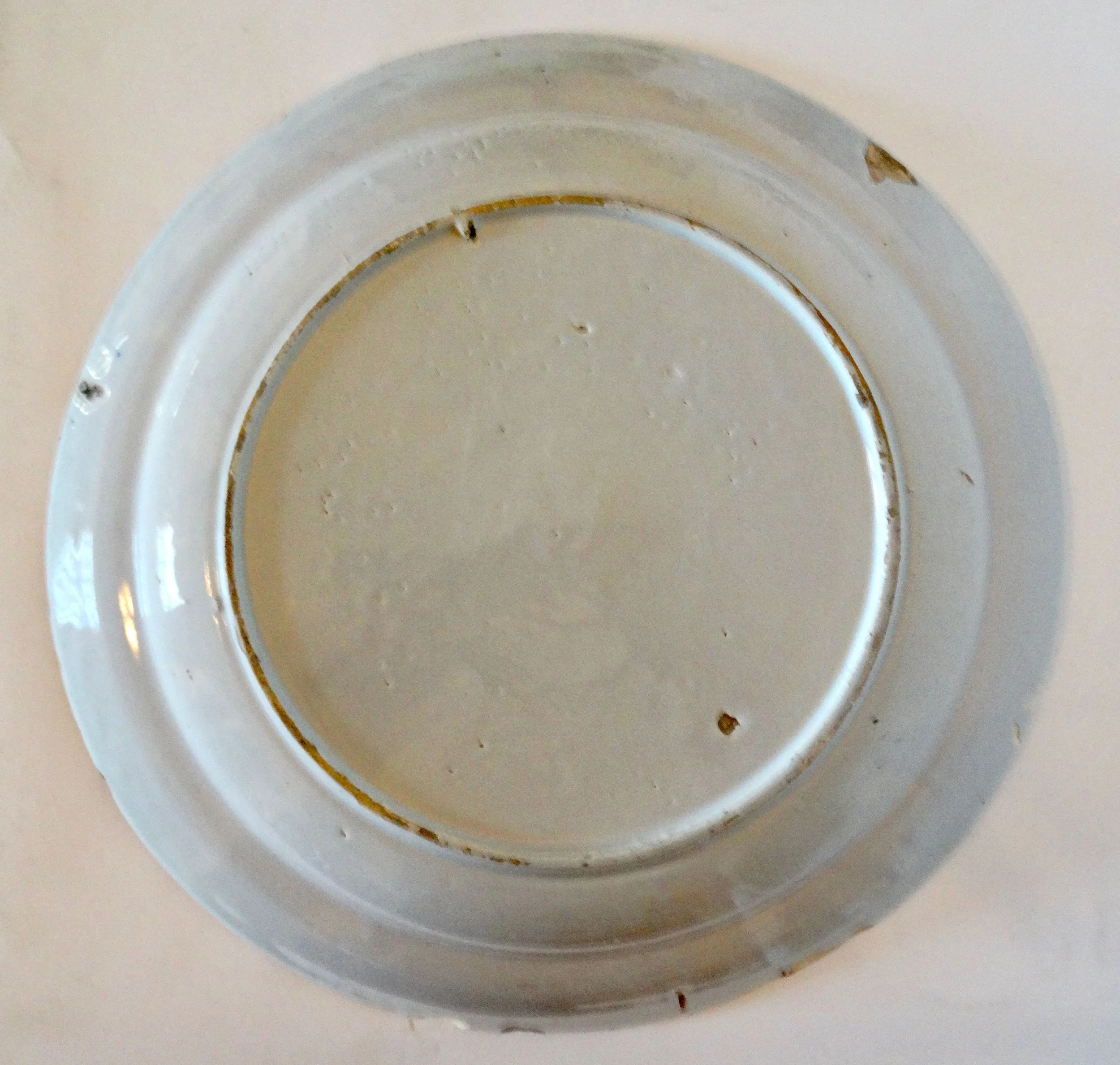 Reverse of antique Delft faience charger with tin glaze.