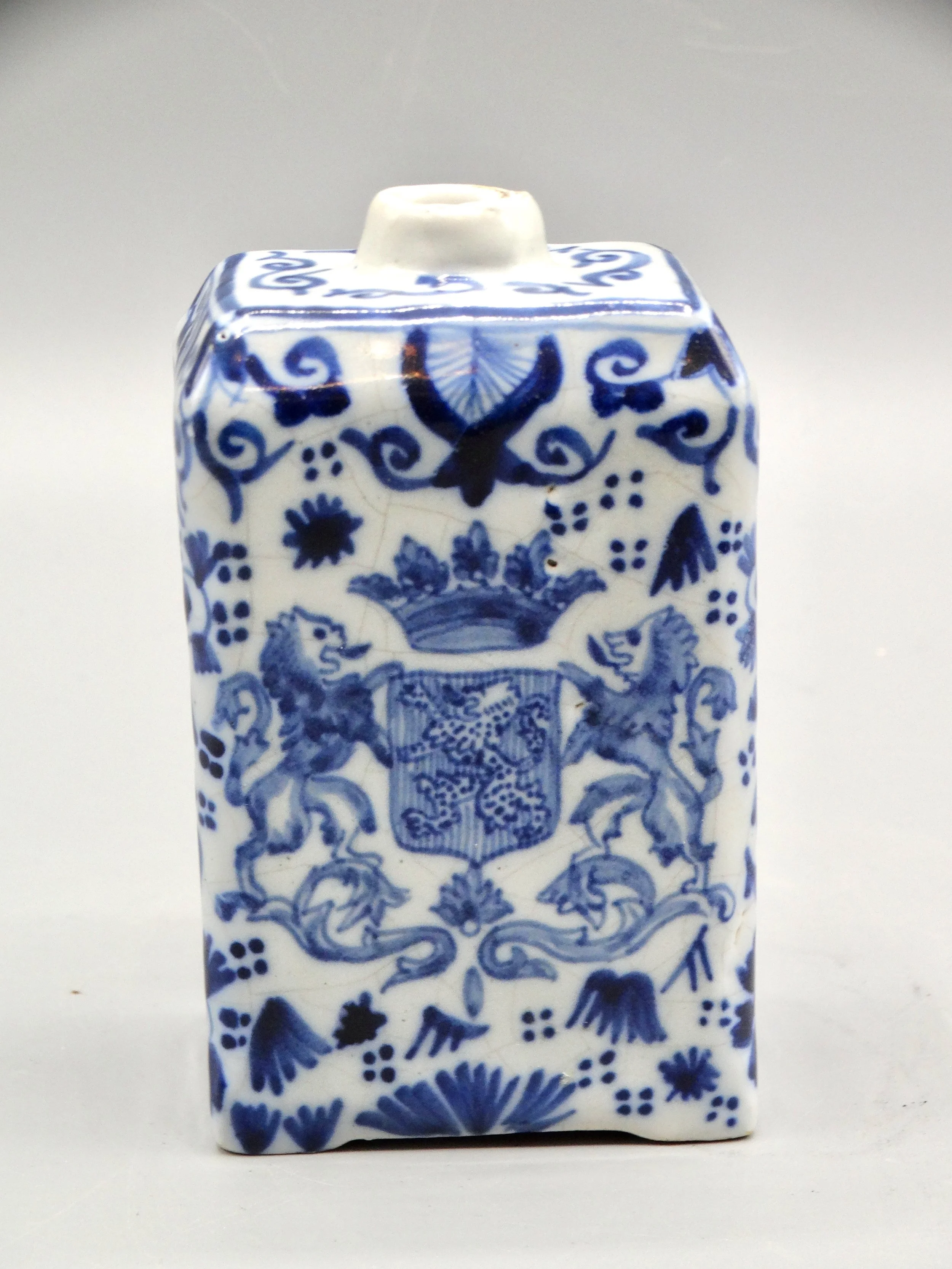 19th-century English Delft tea caddy with hand painted rampart lions, crown coat of arms, bird, and floral motifs.