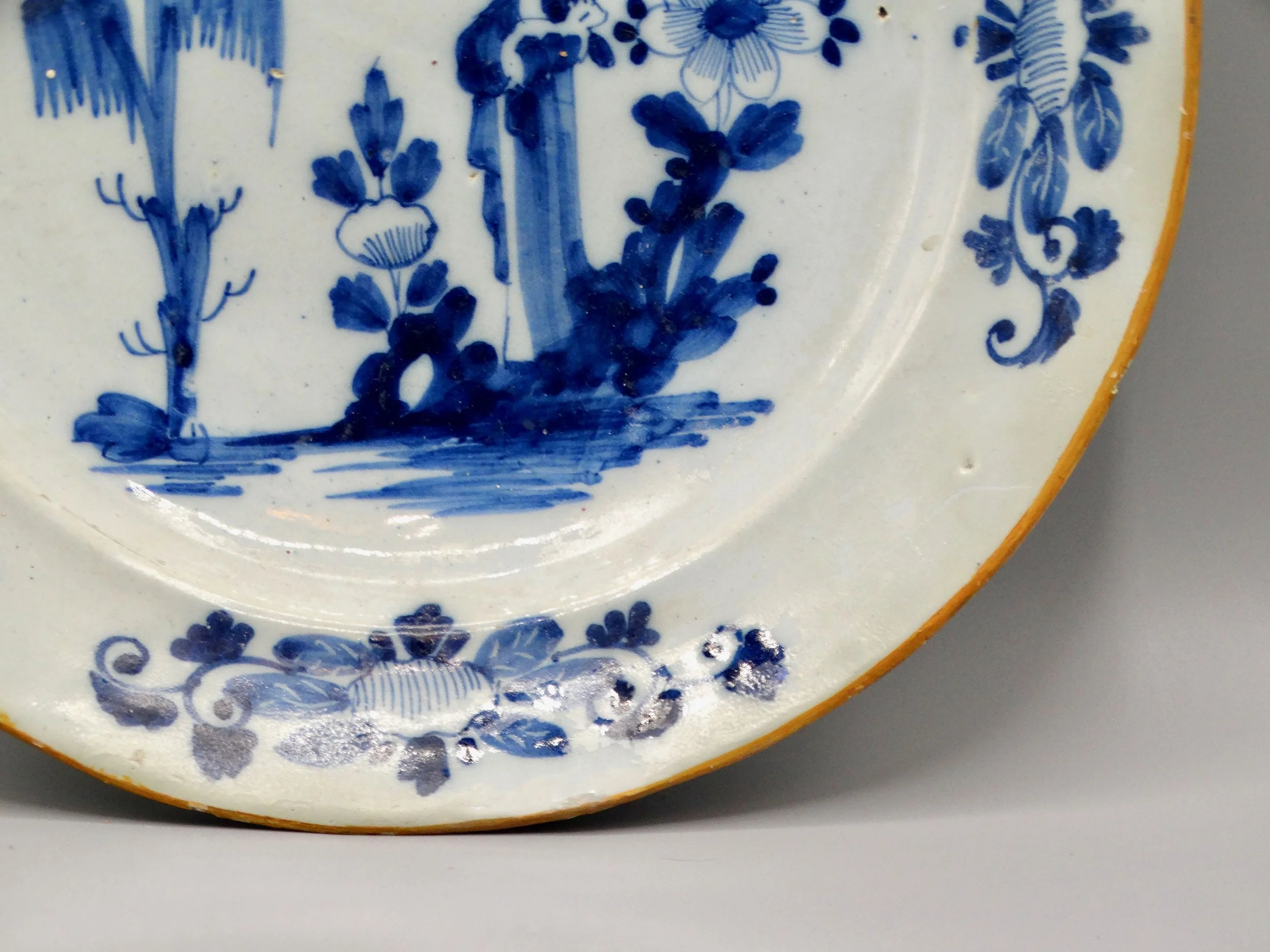 Orange edge and rim detail on 18th-century Dutch Delft figural charger.