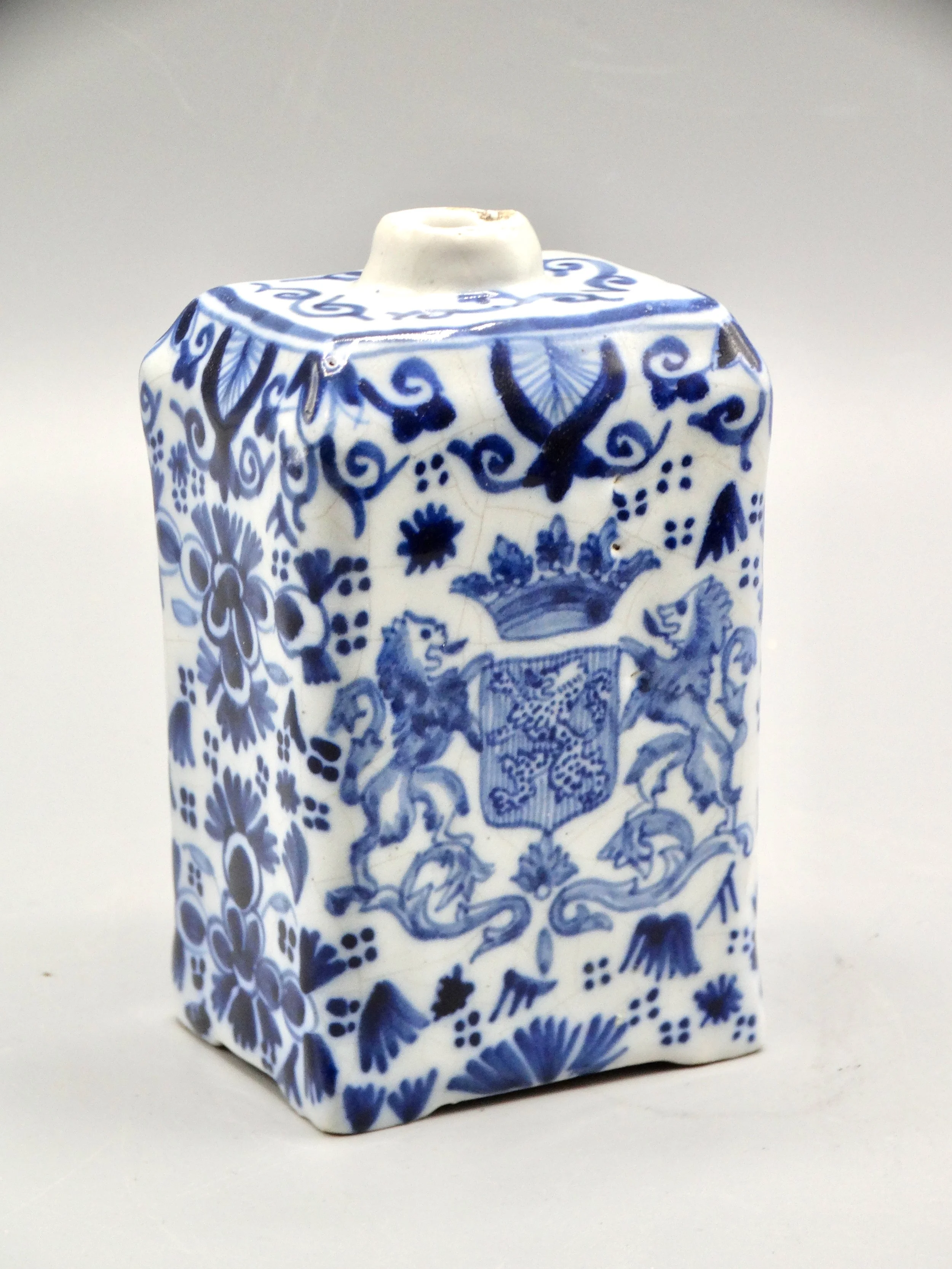 19th-century English Delft tea caddy with hand painted rampart lions, crown coat of arms, bird, and floral motifs.