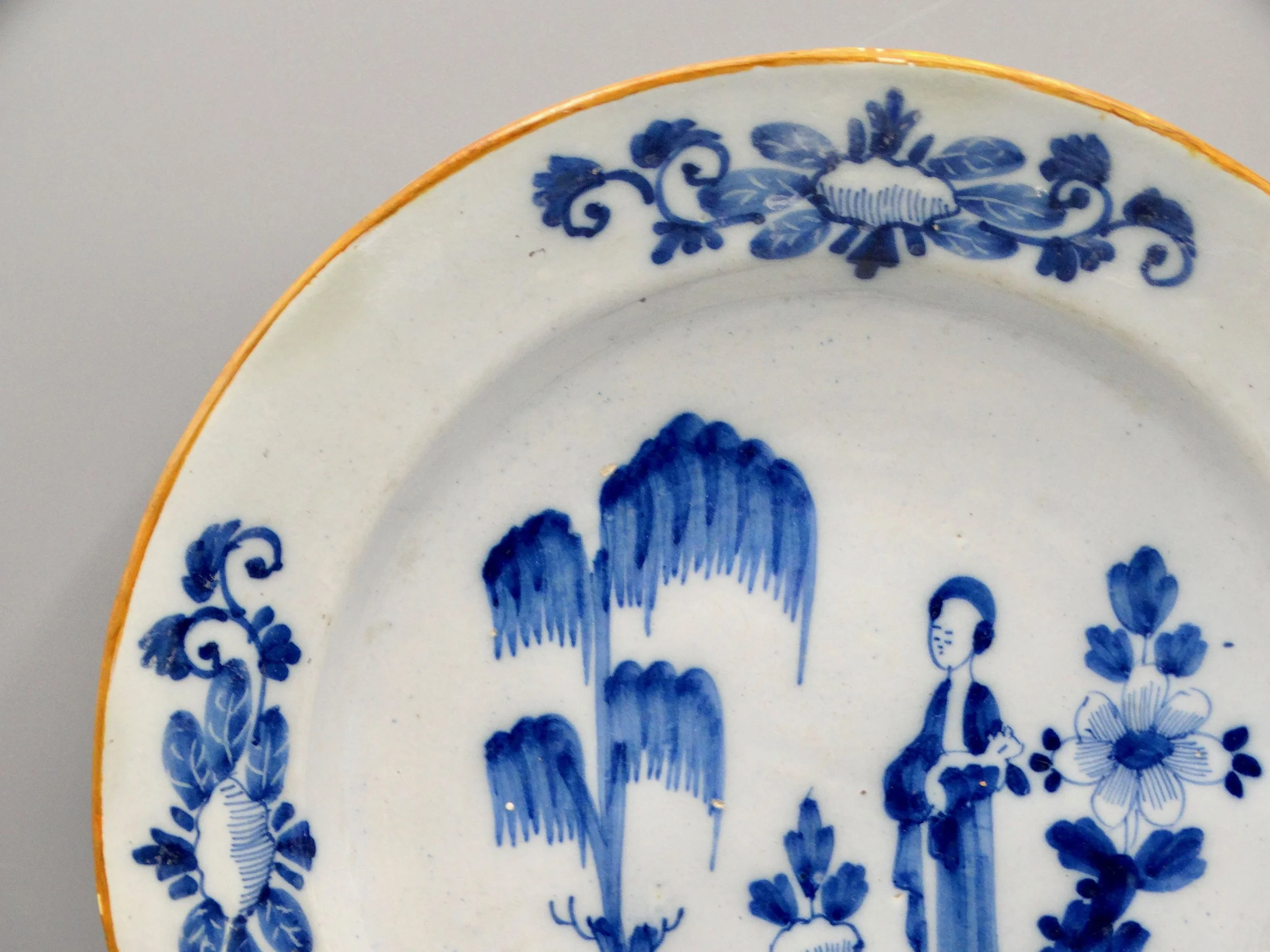 Orange edge and rim detail on 18th-century Dutch Delft figural charger.