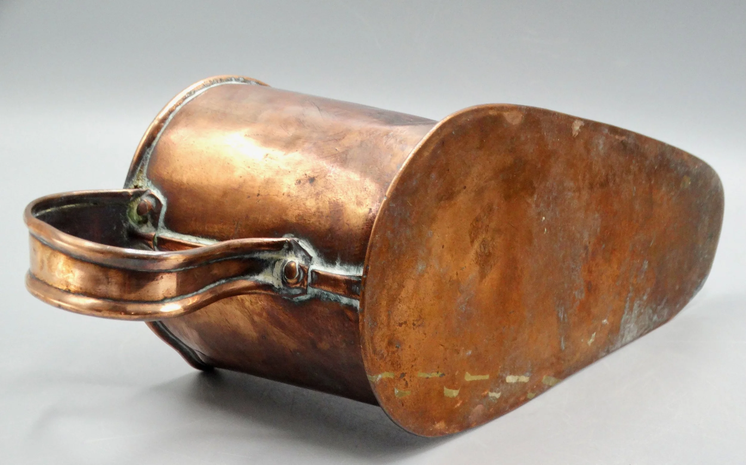 Bottom of antique English copper boot ale warmer, showing flat base and hand-forged copper construction