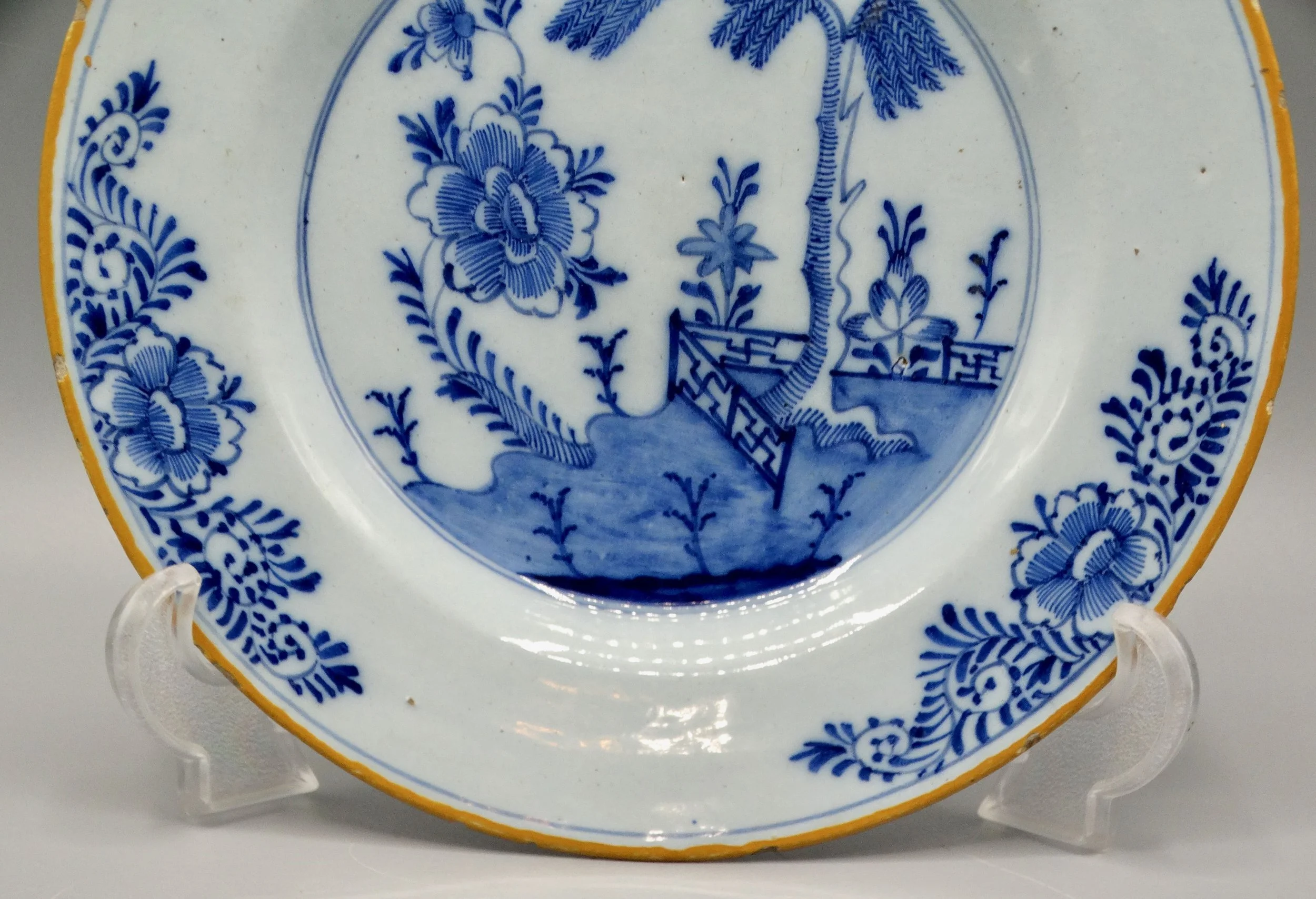 Orange-yellow border and foliate rim detail on second 18th-century Dutch Delft chinoiserie plate.