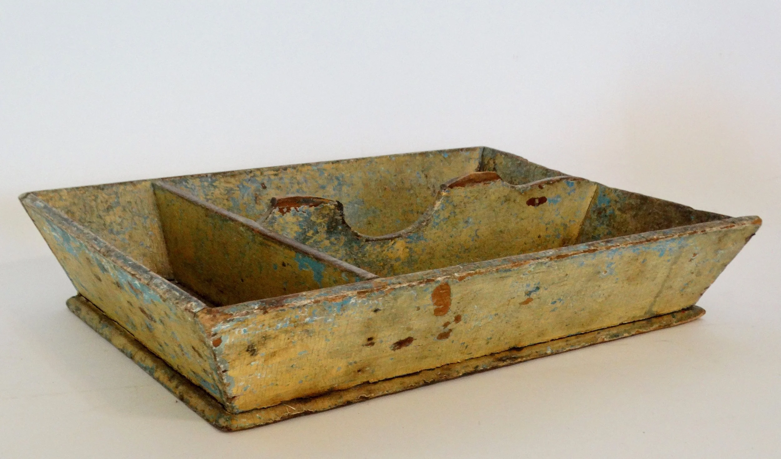 Early 19th-century American primitive cutlery tray in mustard colored paint with canted sides and protruding base.