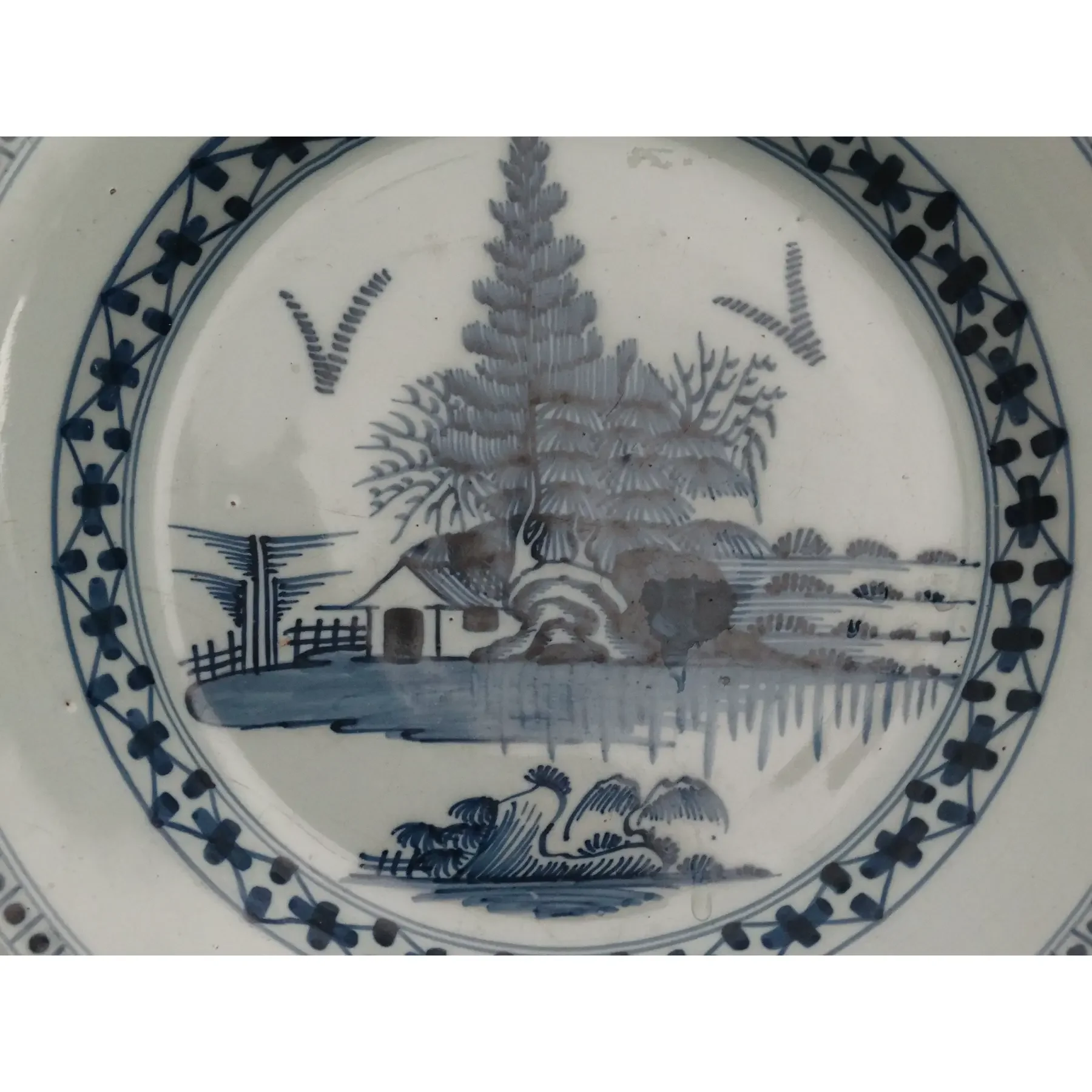 Hand-painted chinoiserie landscape with house, trees, birds, and water on an 18th-century English Delft charger.