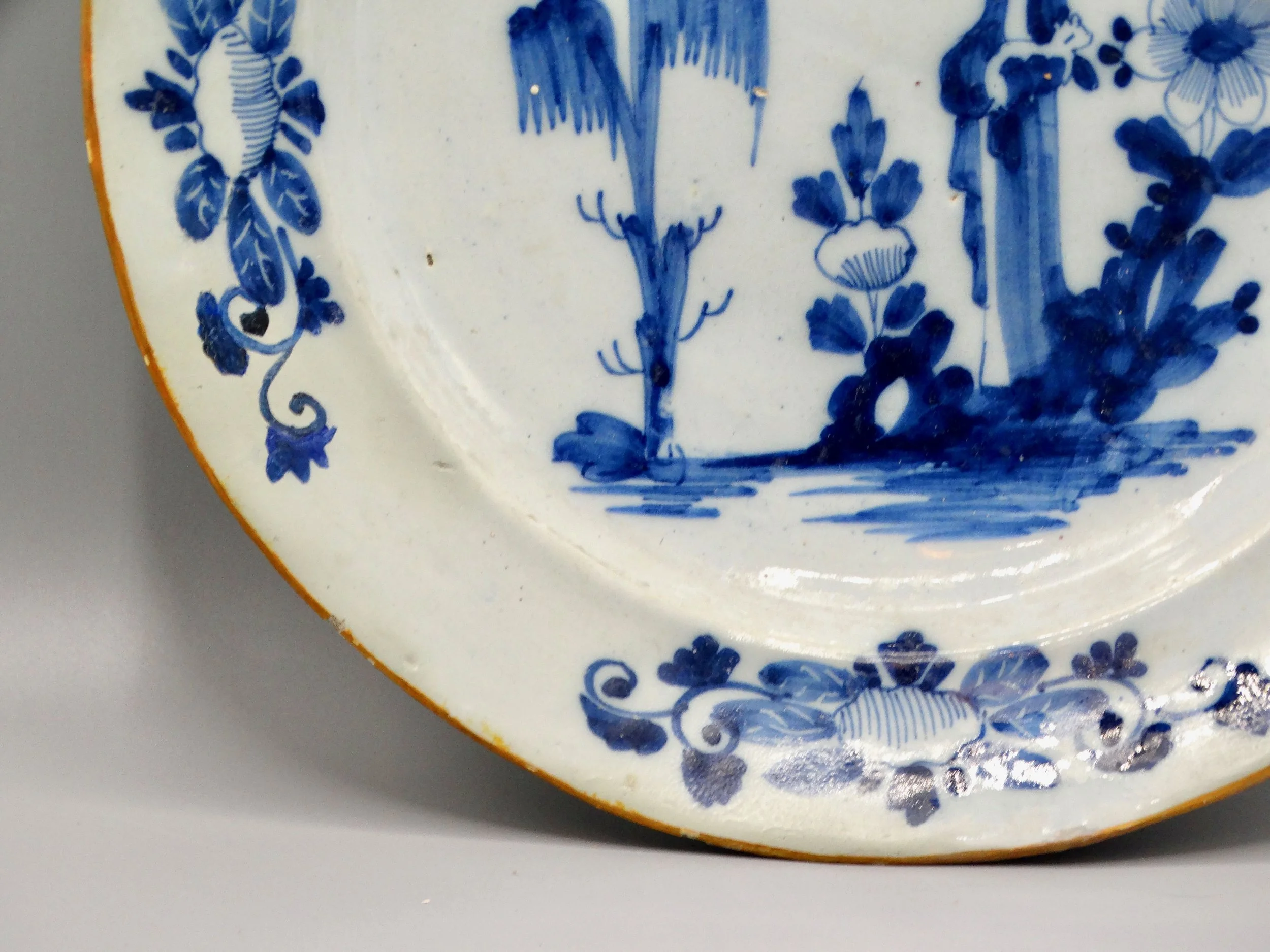 Orange edge and rim detail on 18th-century Dutch Delft figural charger.
