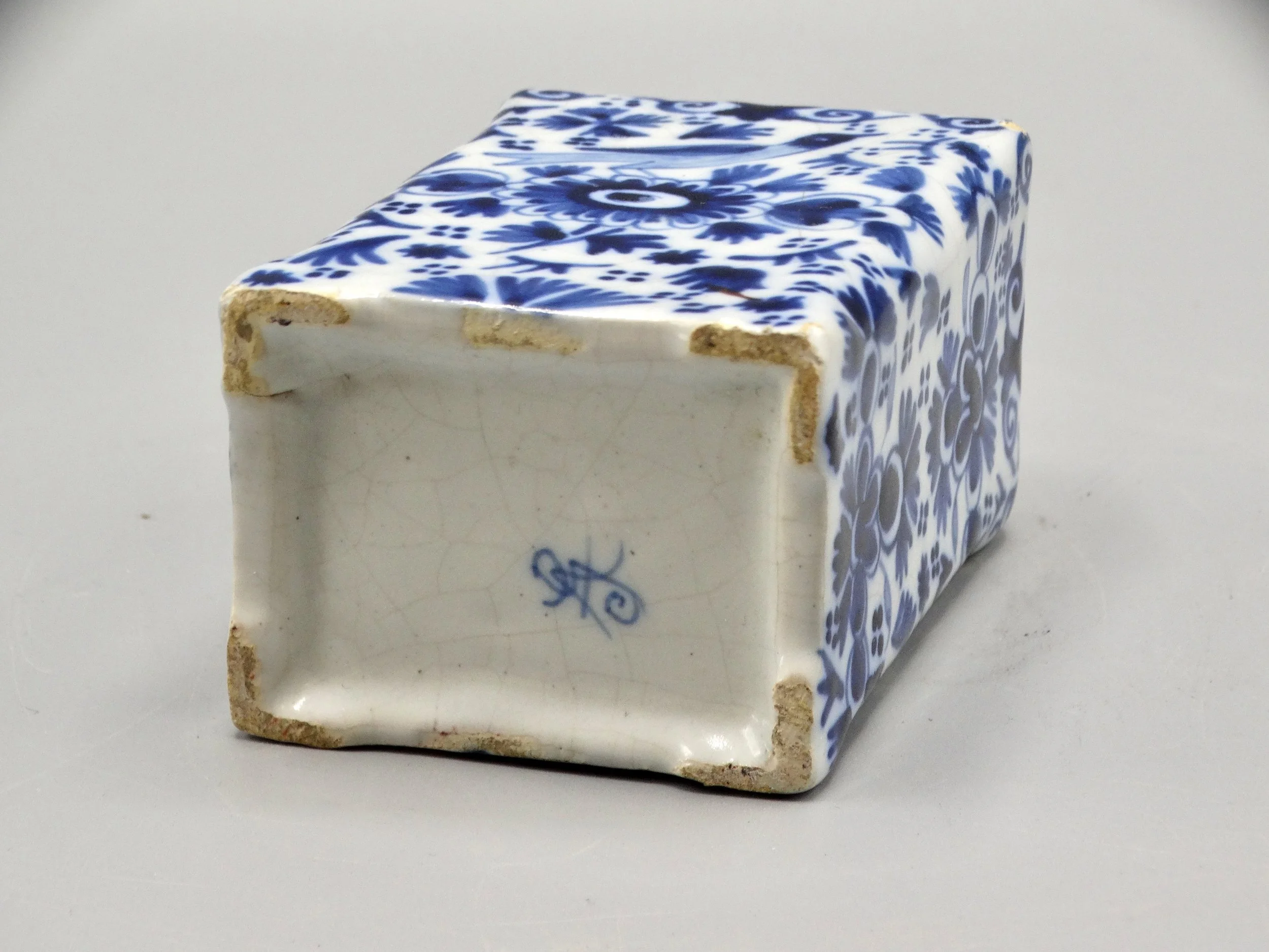 Reverse of 19th-century English Delft tea caddy showing maker’s mark and faience body.