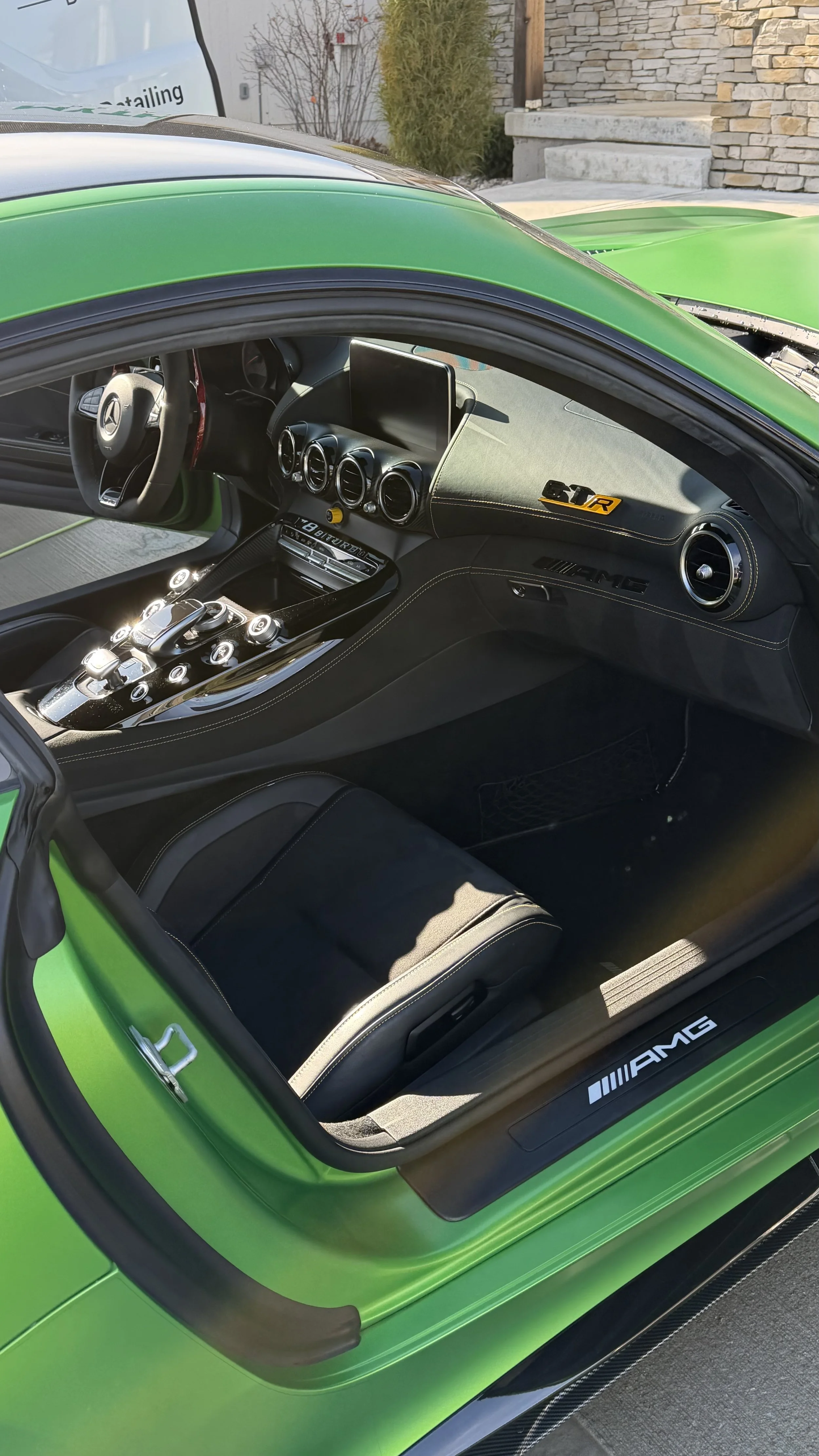 Interior of a green Mercedes-AMG sports car, showing the dashboard, steering wheel, and center console with various controls and a touchscreen display.