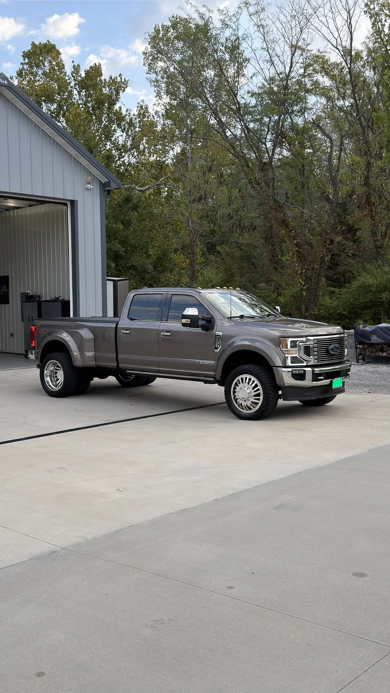 A gray Ford F-150 pickup truck parked in front of a metal building with trees in the background.