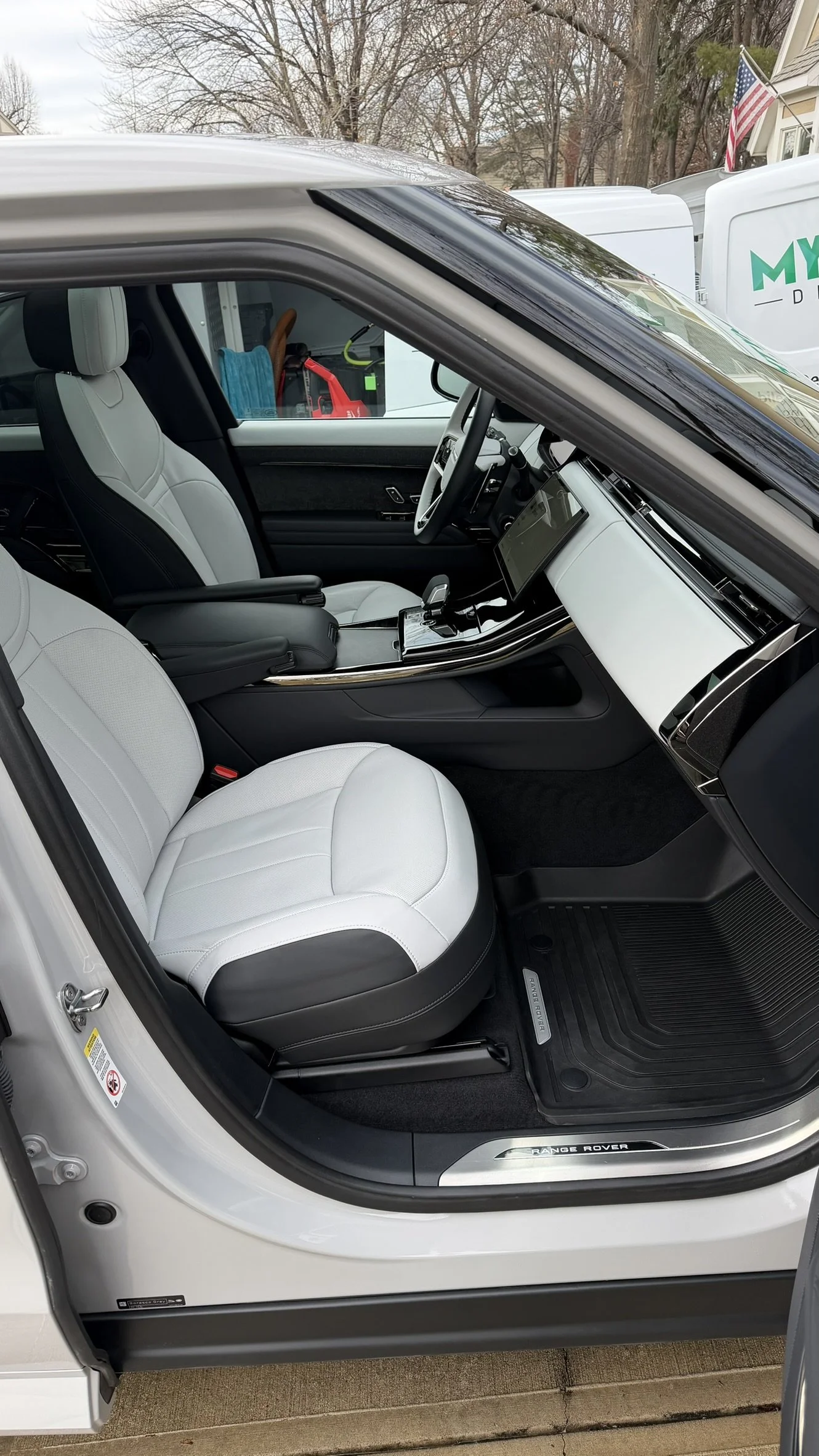 The interior of a white Range Rover vehicle showing the front passenger and driver seats, dashboard, and center console.